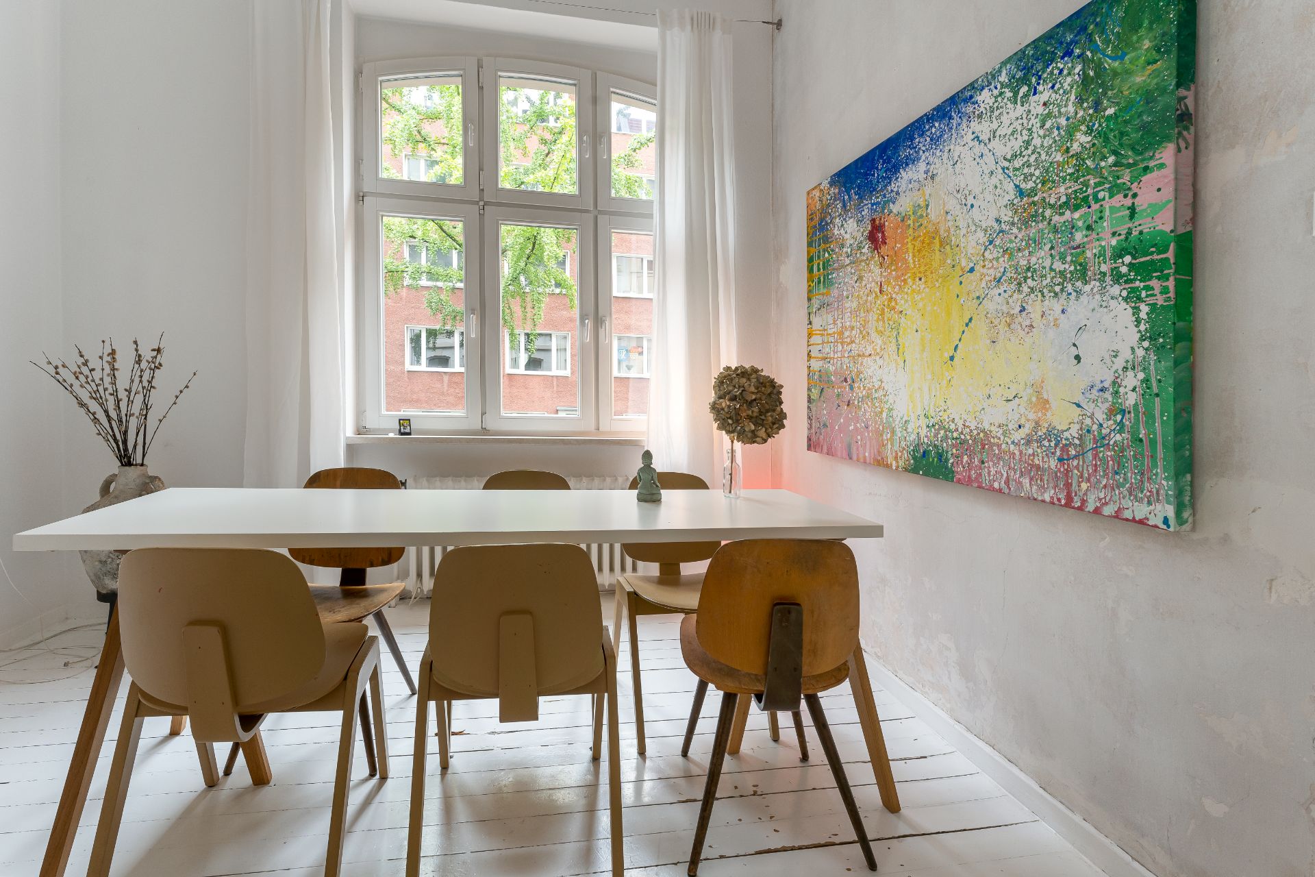 Heller Essbereich mit Holztisch, sechs Stühlen und großem buntem Gemälde an der Wand.