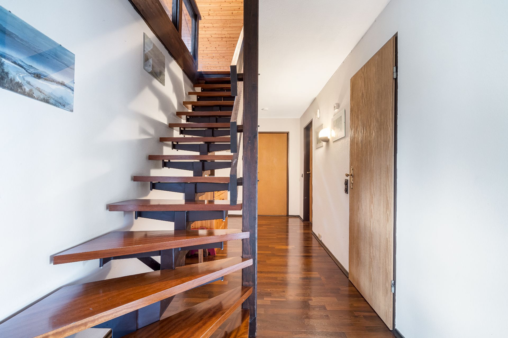 Flur mit Holztreppe, Holzfußboden und mehreren Türen in einem Wohnhaus.