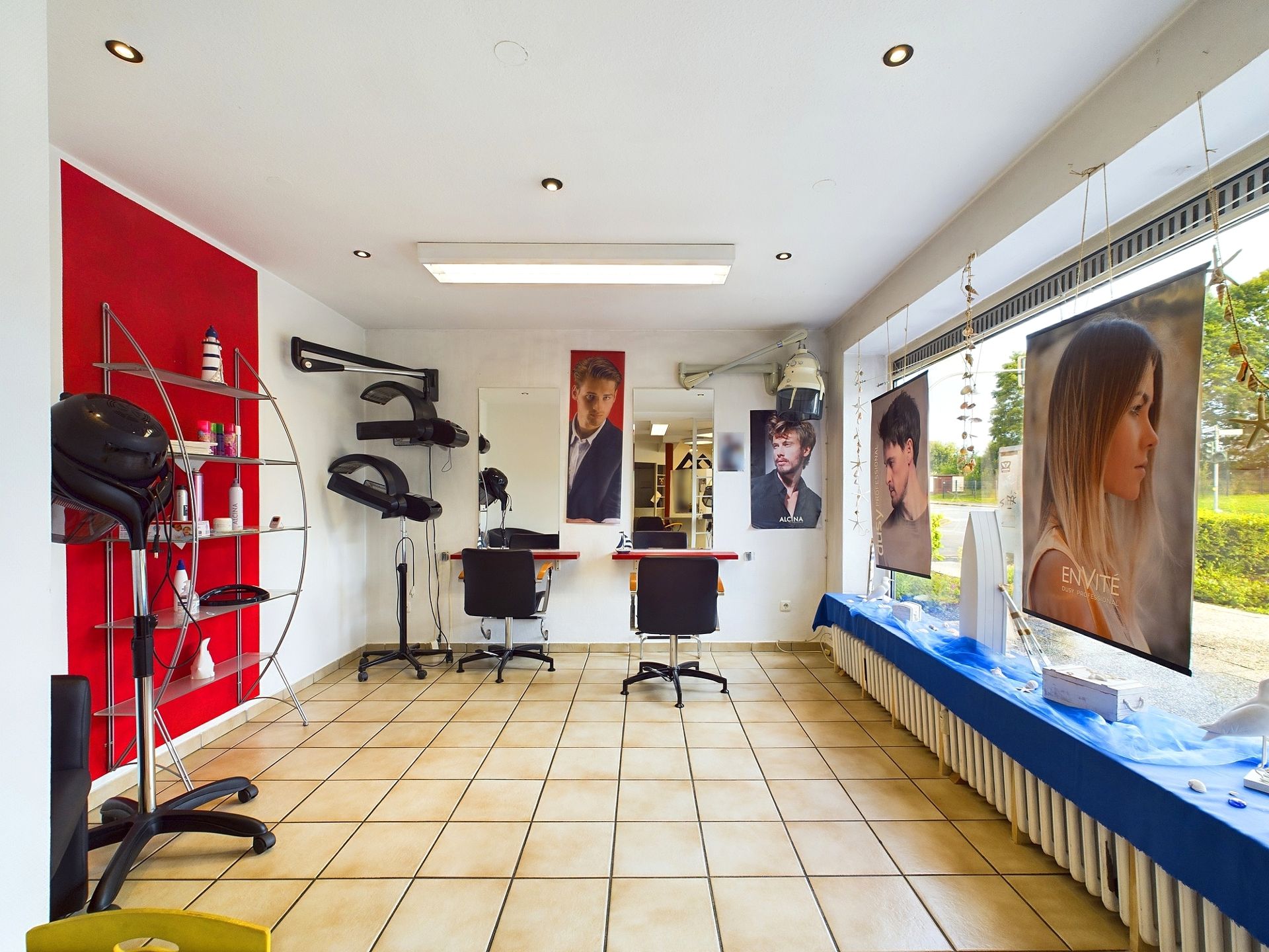 Heller Raum mit zwei Frisierstühlen, großen Fenstern und Friseurausstattung.