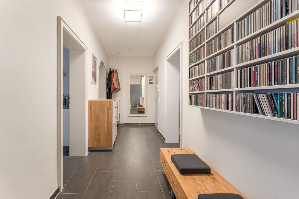 Flur mit Holzbank, CD-Regal an der Wand, Spiegel und Garderobe im Hintergrund.