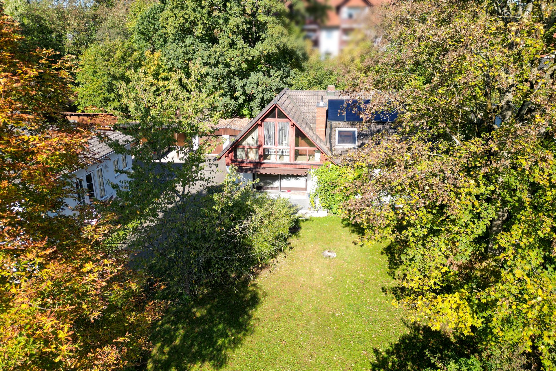 Zweistöckiges Haus mit Giebeldach und großem Garten, umgeben von Bäumen.