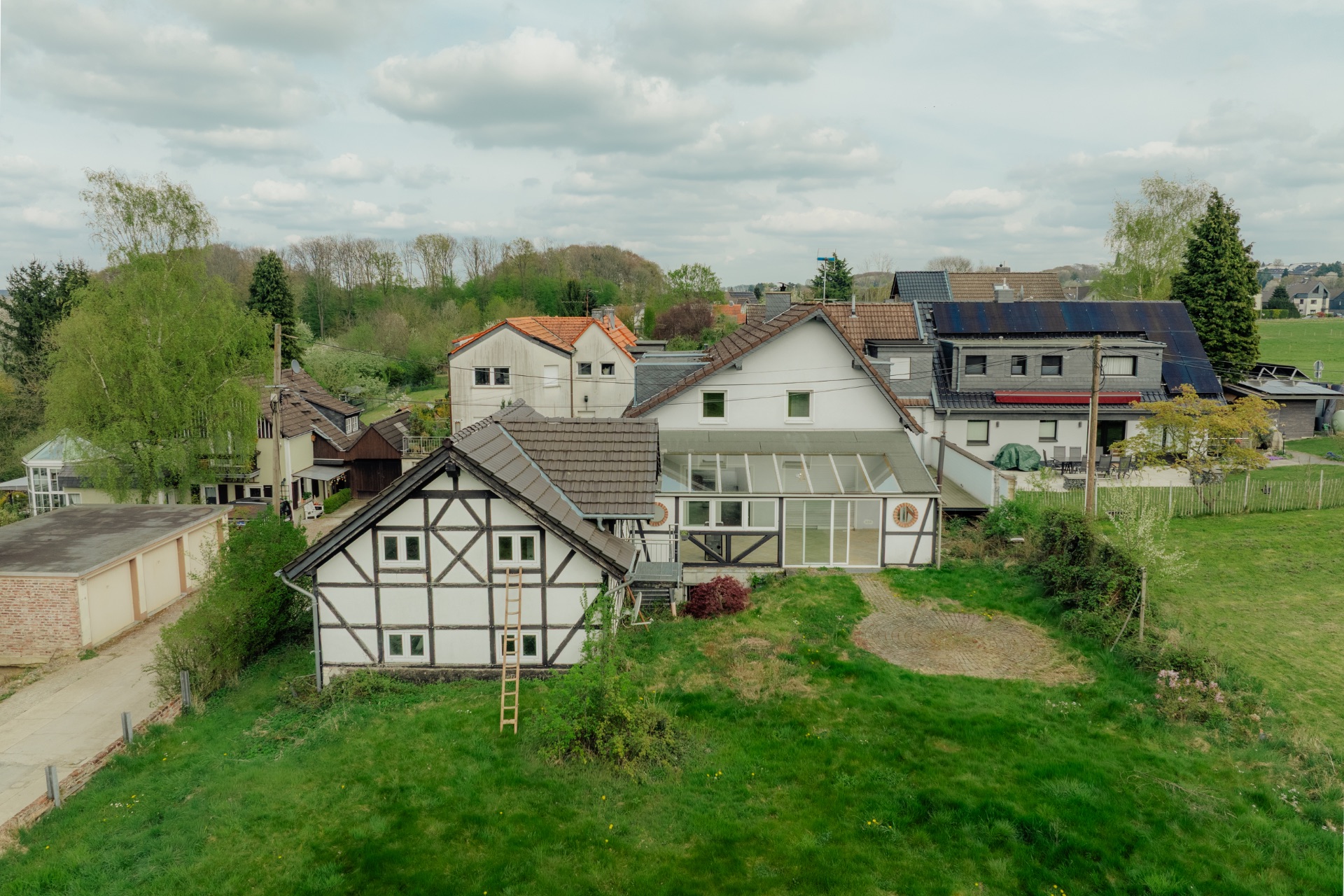 Mehrere Wohnhäuser mit Fachwerkfassade und Wintergarten, umgeben von viel Grün.
