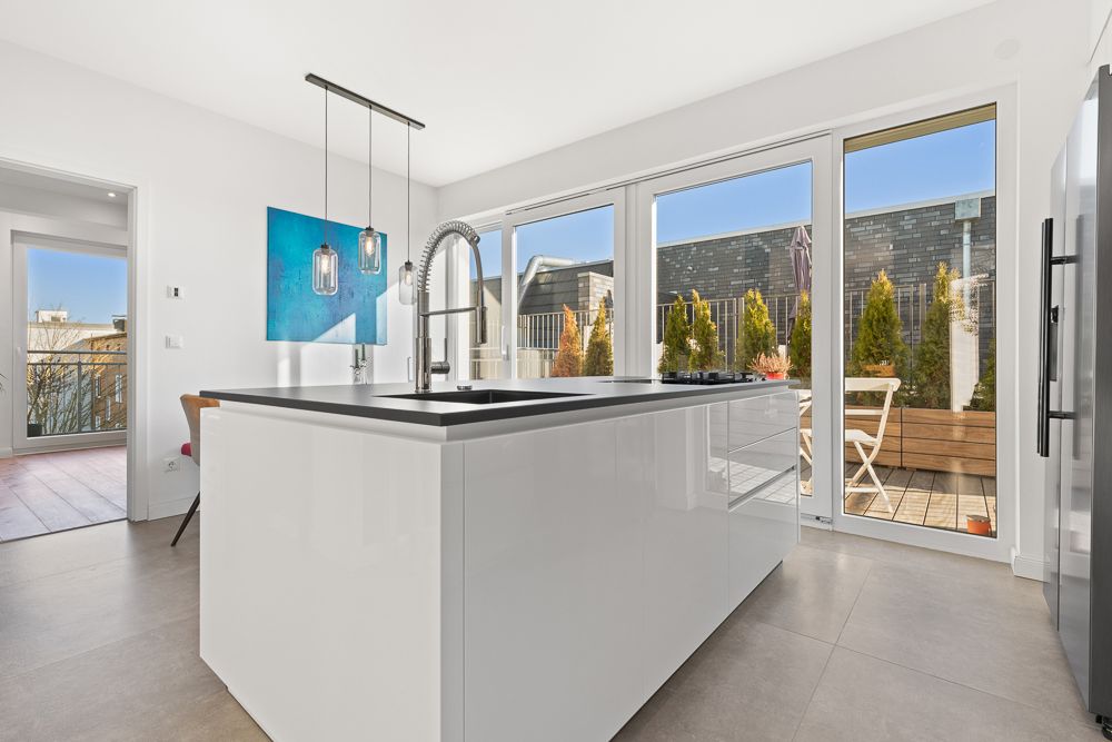 Moderne Küche mit Kochinsel und Zugang zur Terrasse mit Sitzbereich und Pflanzen.
