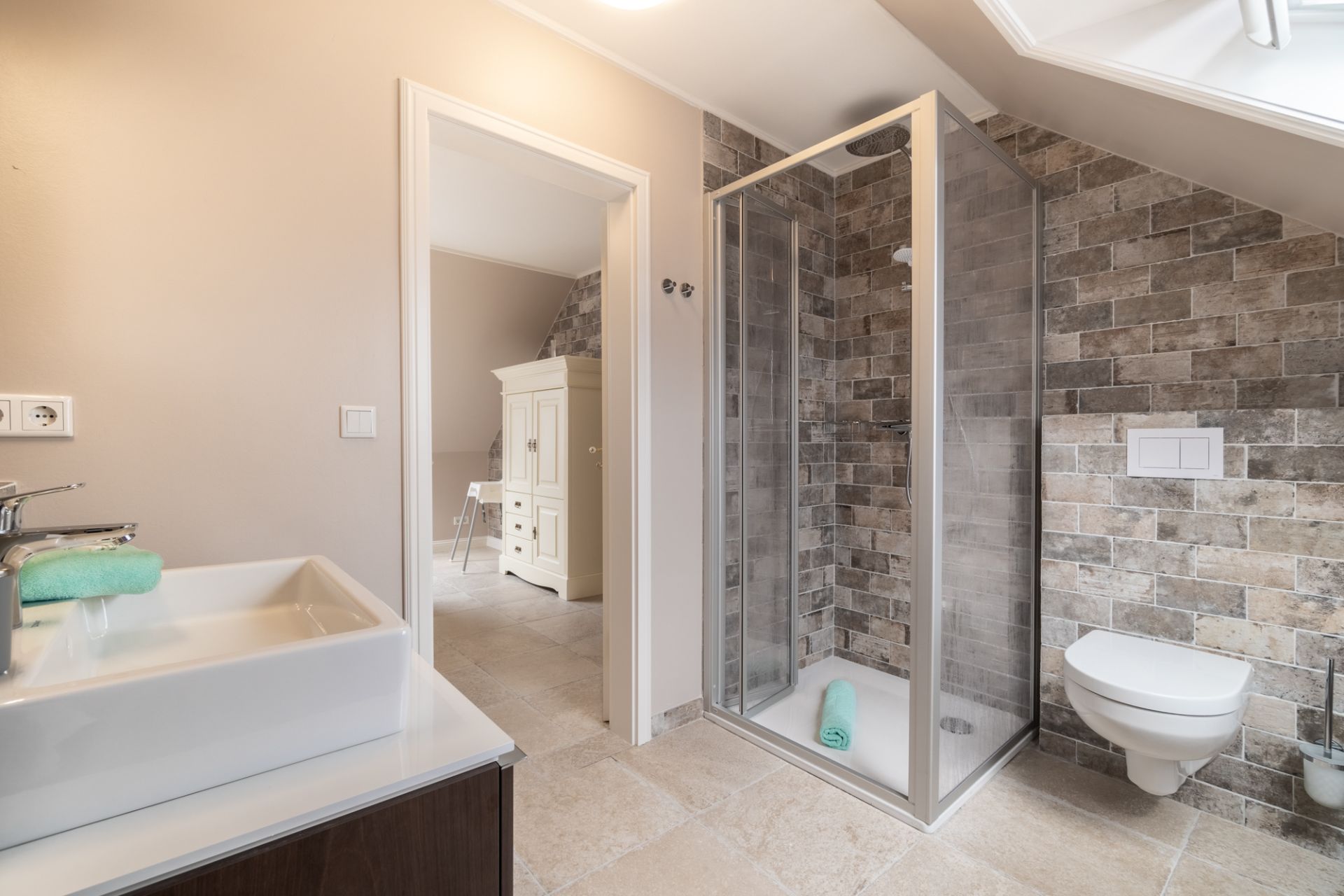 Modernes Badezimmer mit Dusche, Waschbecken und Wandtoilette, Zugang zu einem anderen Raum.
