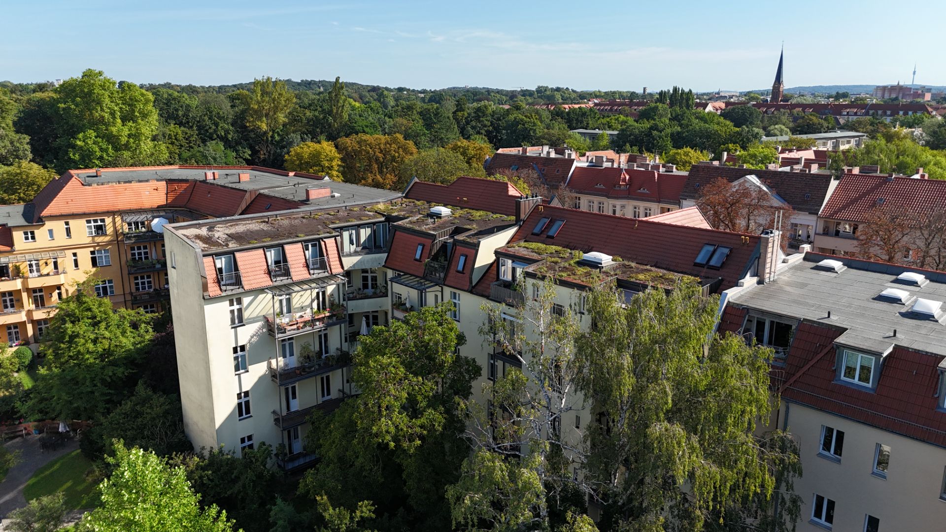 Mehrere Wohnhäuser mit roten Dächern und Bäumen im Vordergrund, aufgenommen aus der Vogelperspektive.
