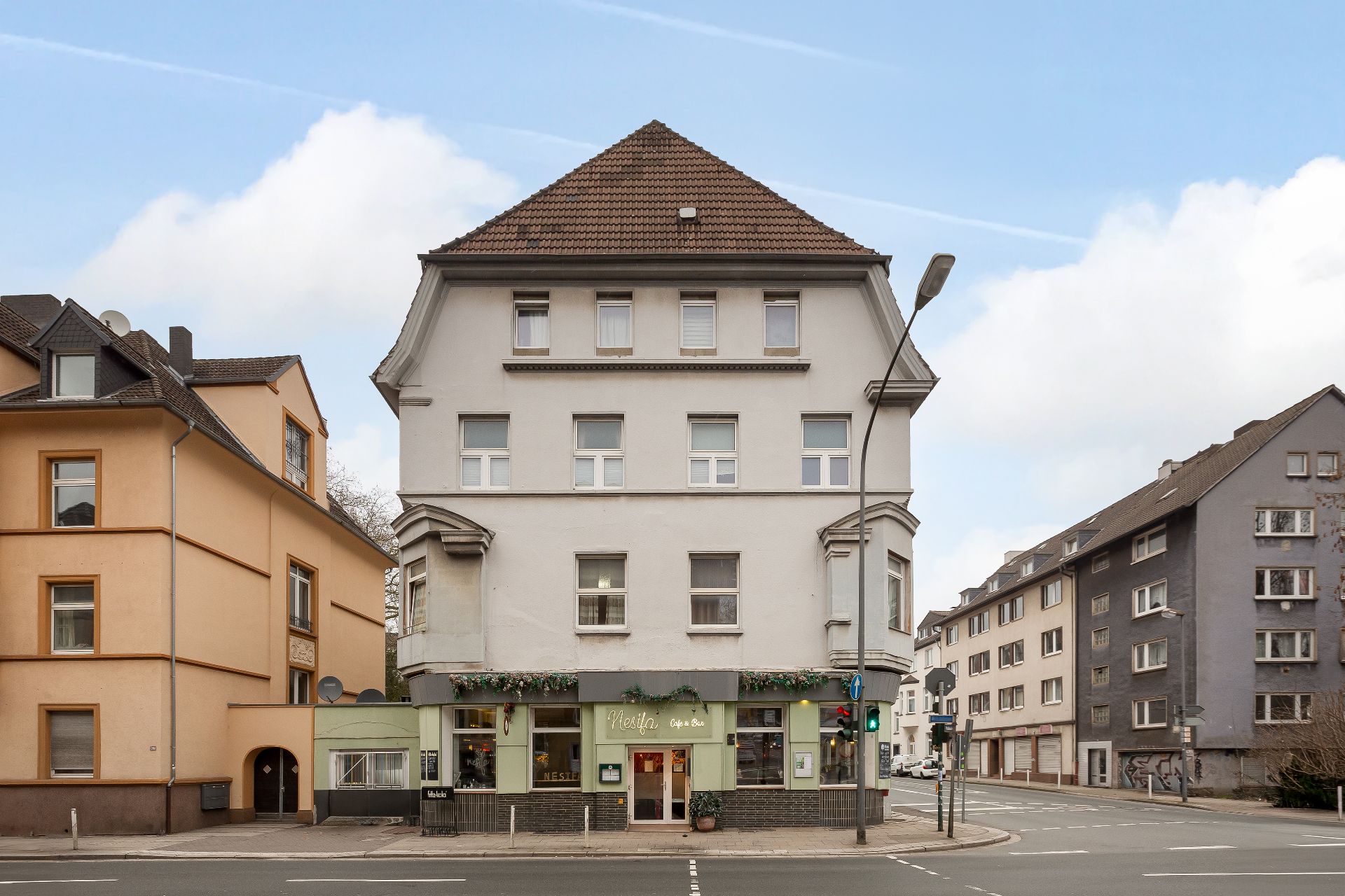 Dreistöckiges Wohnhaus mit Geschäft im Erdgeschoss an einer Straßenecke.