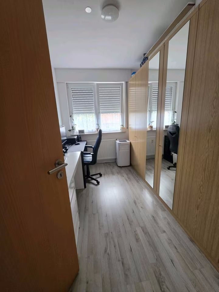 Arbeitszimmer mit Schreibtisch, Bürostuhl und großem Kleiderschrank mit Spiegeln.