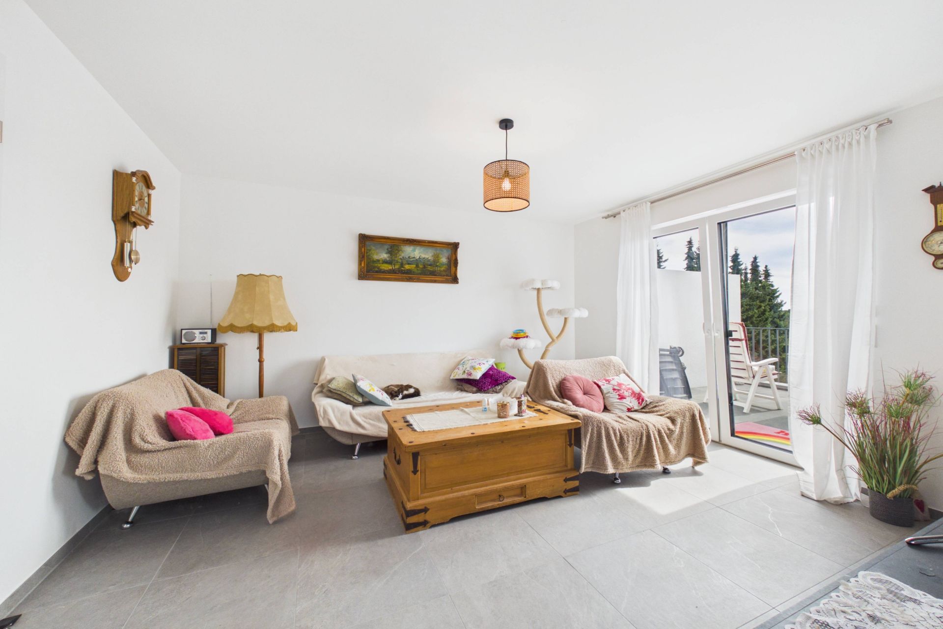 Helles Wohnzimmer mit zwei Sofas, Couchtisch, Stehlampe und Zugang zu einem Balkon.