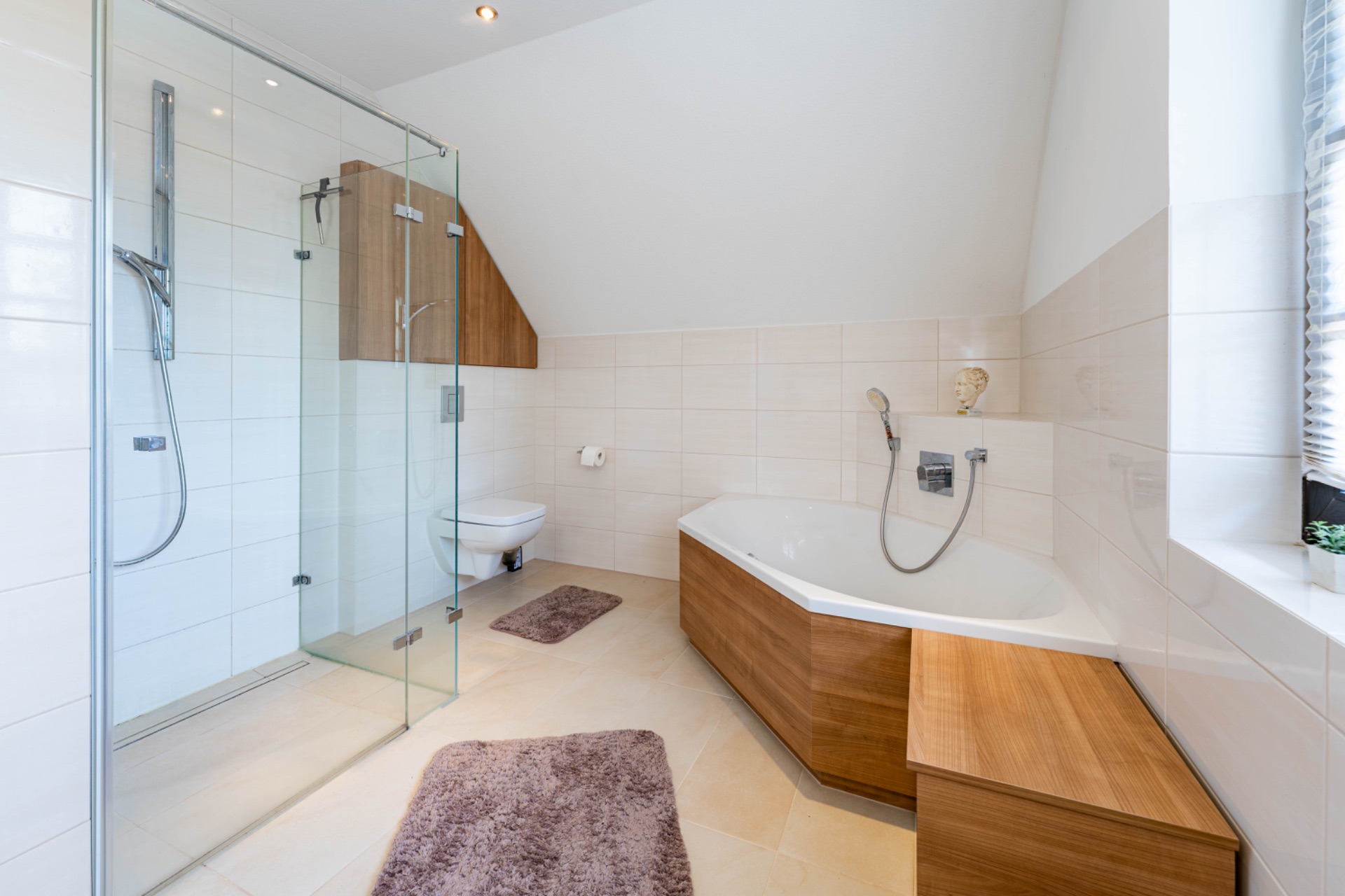 Modernes Badezimmer mit Glasdusche, Badewanne, WC und Holzmöbeln.