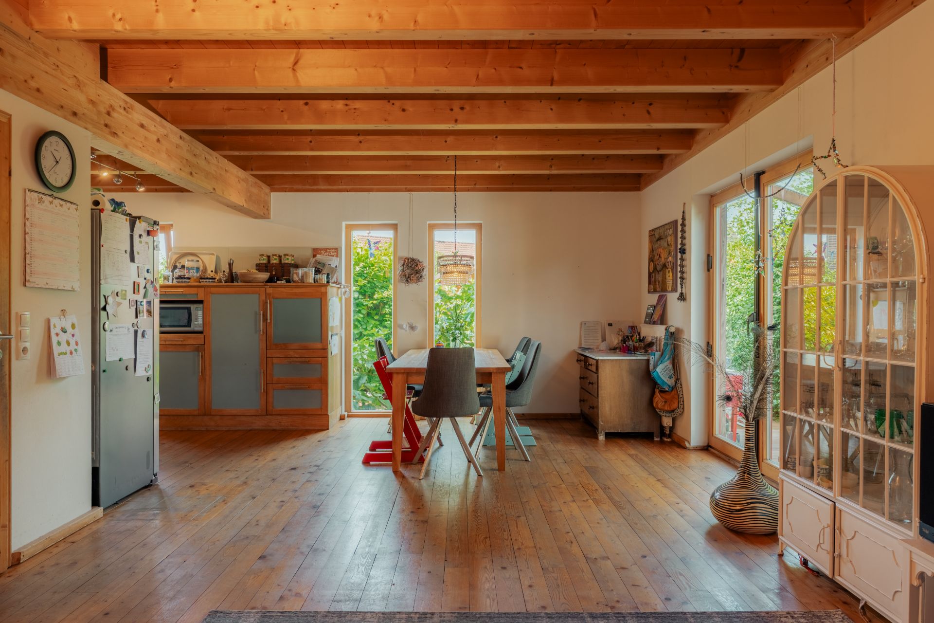 Helles Esszimmer mit Holzboden, Holzbalkendecke, Esstisch und Blick in den Garten.