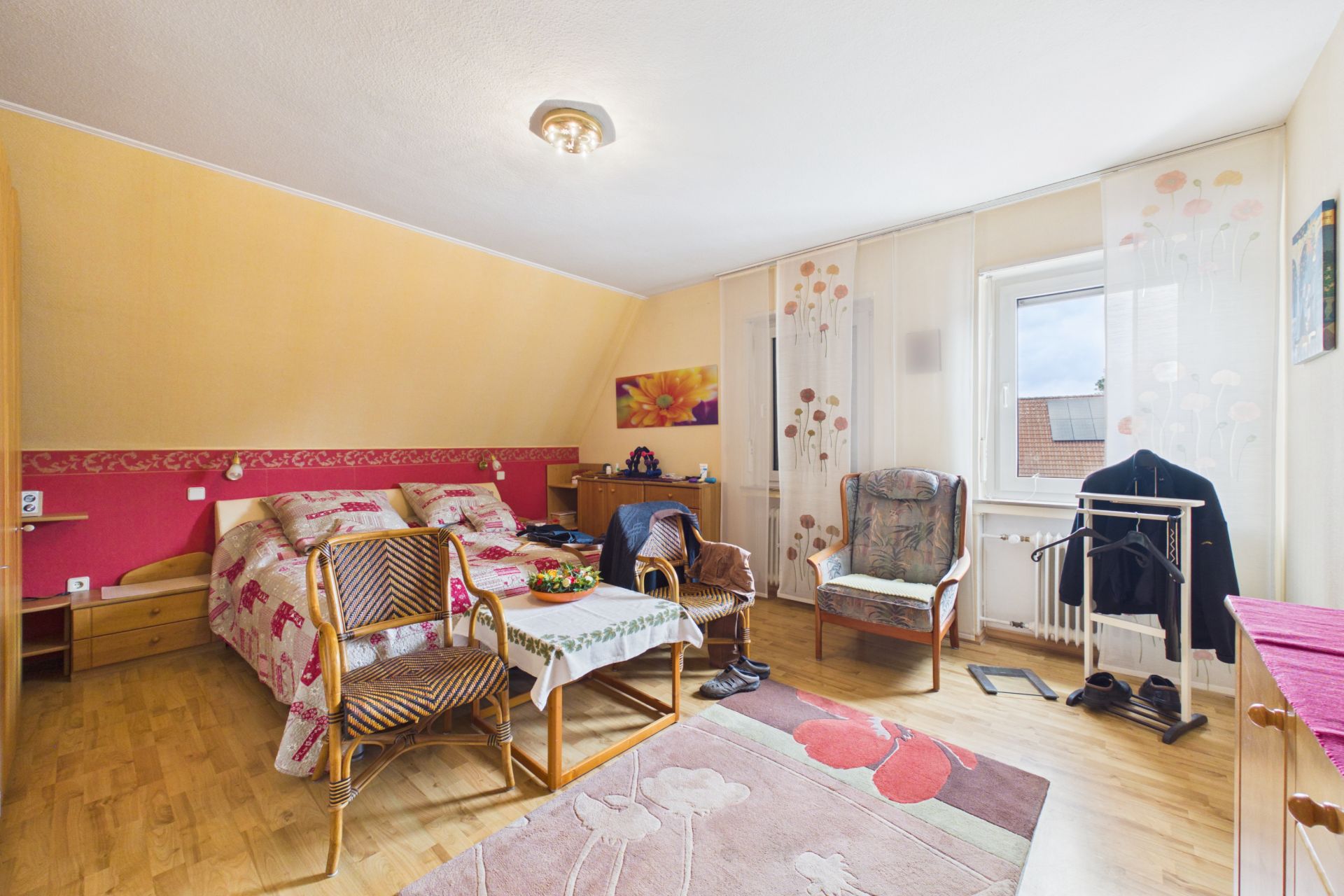 Gemütliches Schlafzimmer mit Doppelbett, Sitzgruppe, Tisch und Fenster mit Vorhängen.