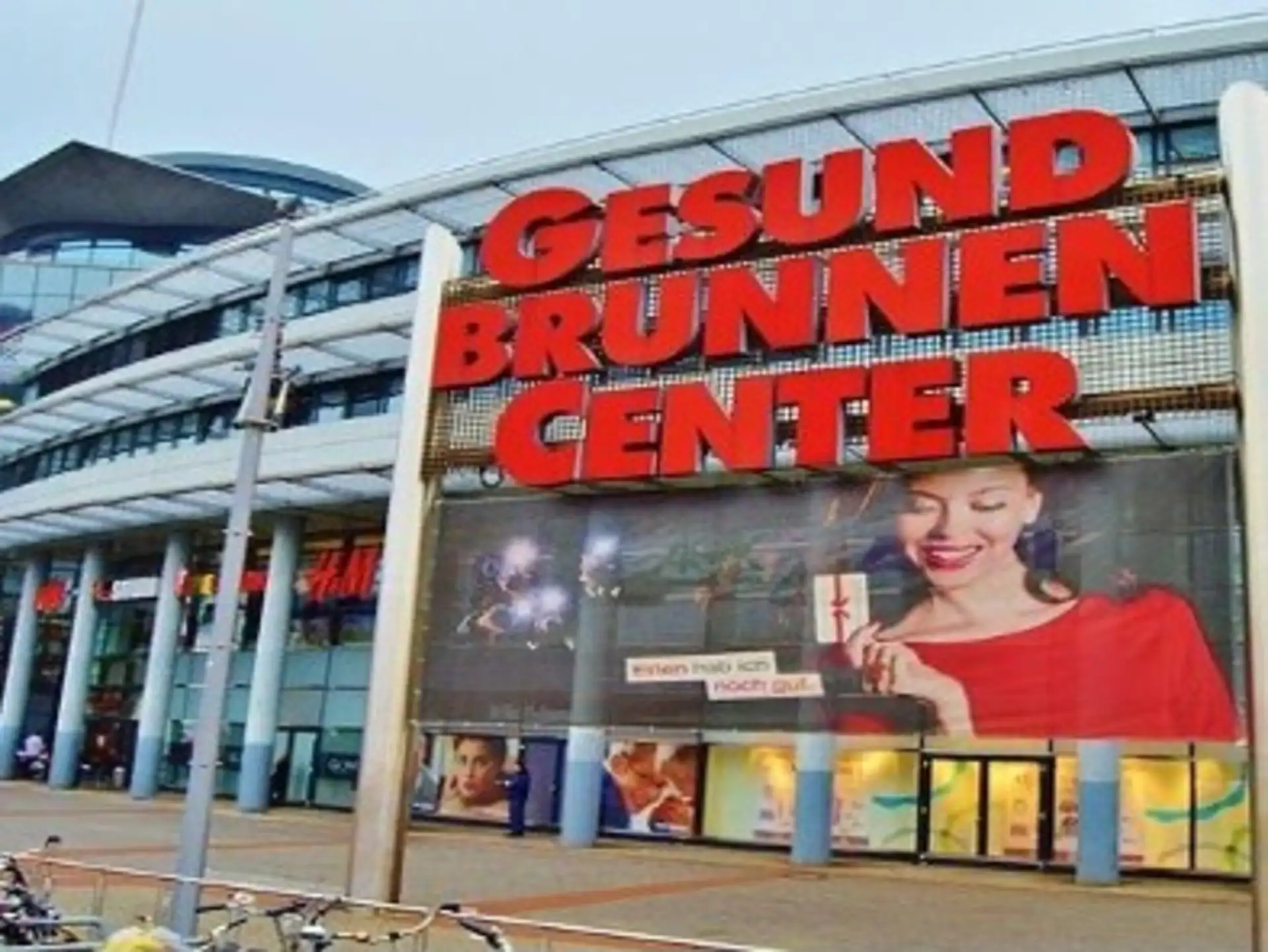 Eingang eines Einkaufszentrums mit großem roten Schriftzug 'Gesundbrunnen Center'.
