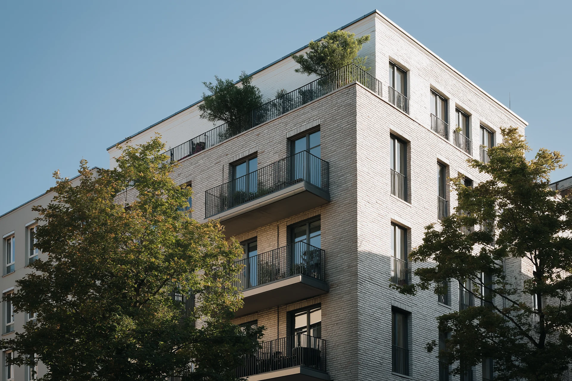Moderne Wohngebäude mit Balkonen und einem Gehweg durch eine begrünte Anlage.