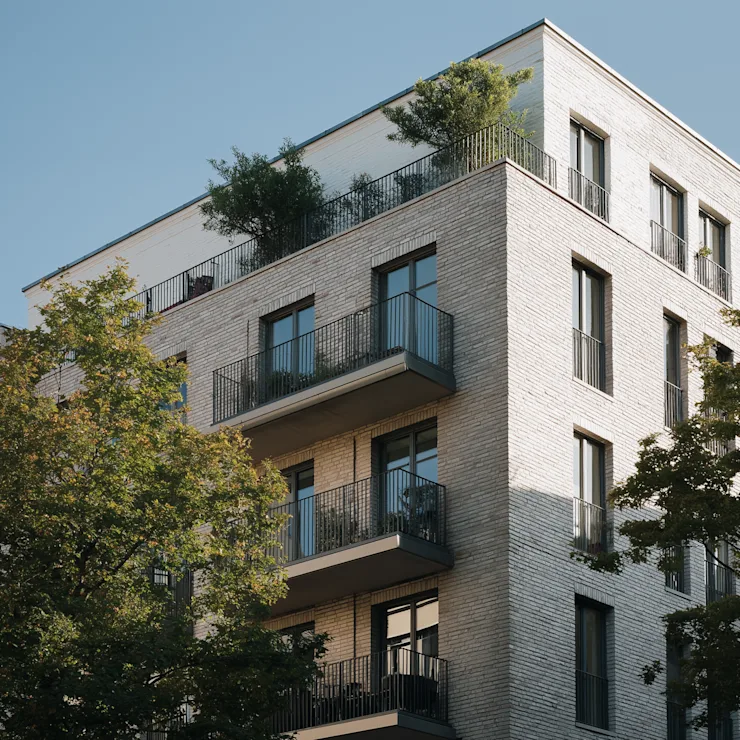Moderne Wohngebäude mit Balkonen und einem Gehweg durch eine begrünte Anlage.