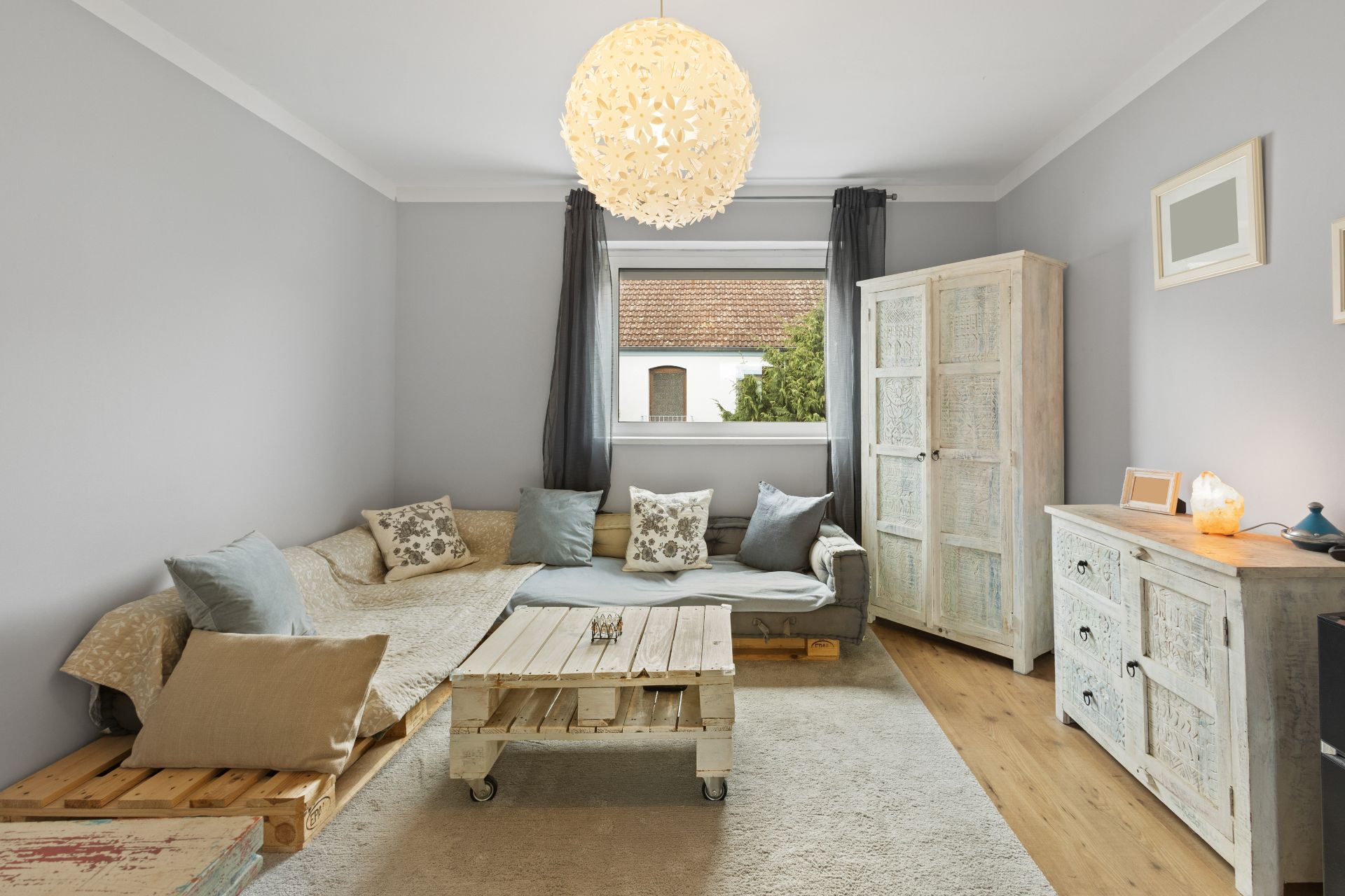 Helles Wohnzimmer mit Sofa, Couchtisch auf Rollen, Schrank und Kommode aus hellem Holz.