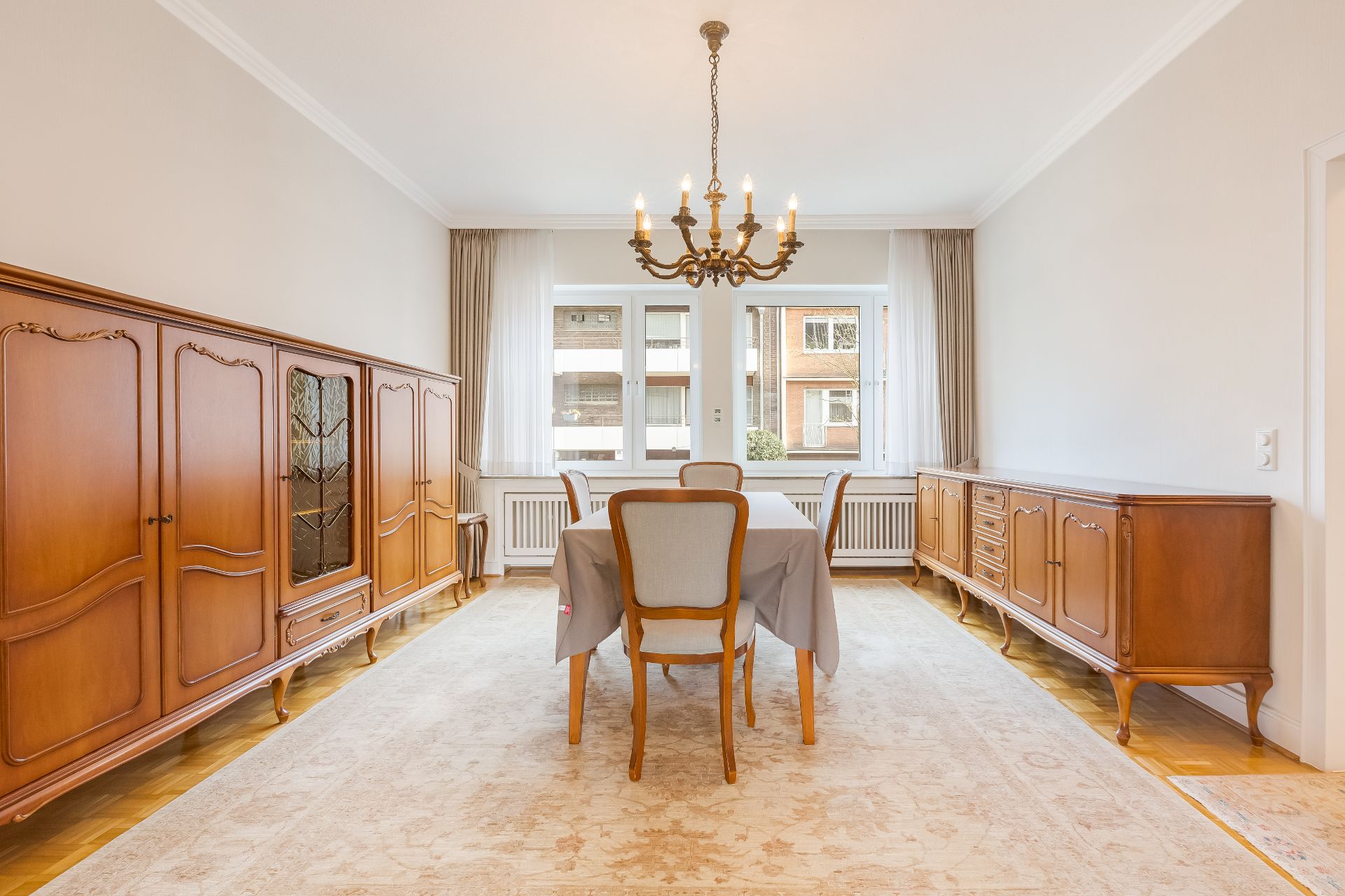 Heller Esszimmer mit Holzmöbeln, Tisch, vier Stühlen und Kronleuchter.