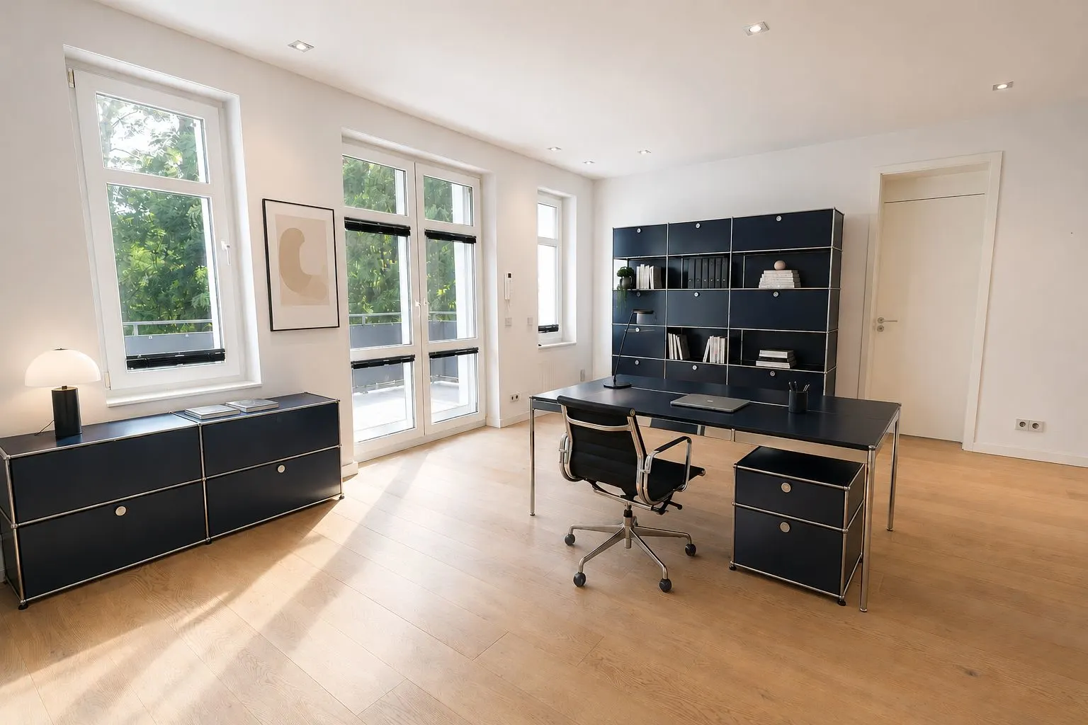 Modernes Arbeitszimmer mit großem Schreibtisch, Regalen und viel Tageslicht durch große Fenster.