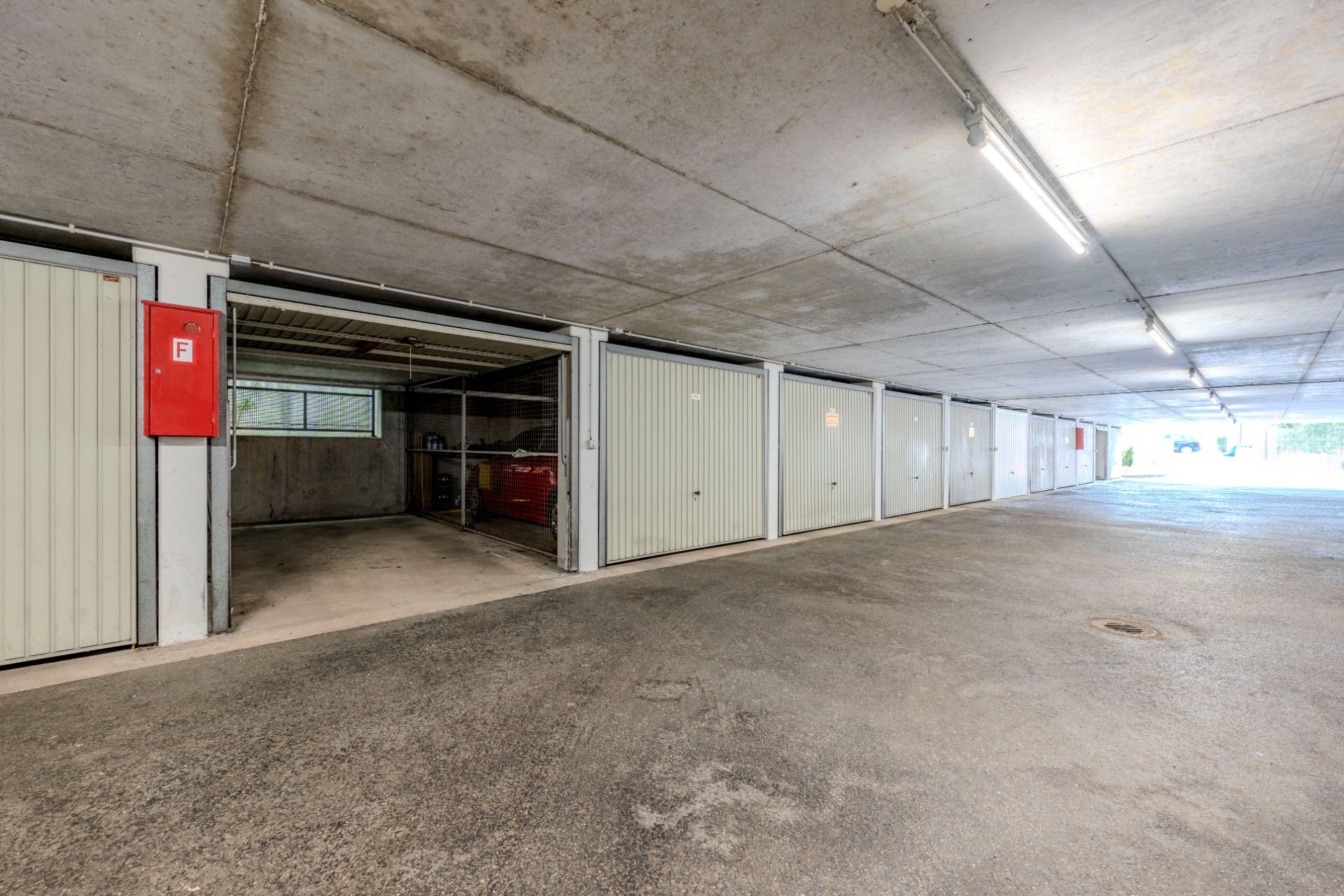 Reihe von Garagen mit offenen und geschlossenen Toren in einer Tiefgarage.