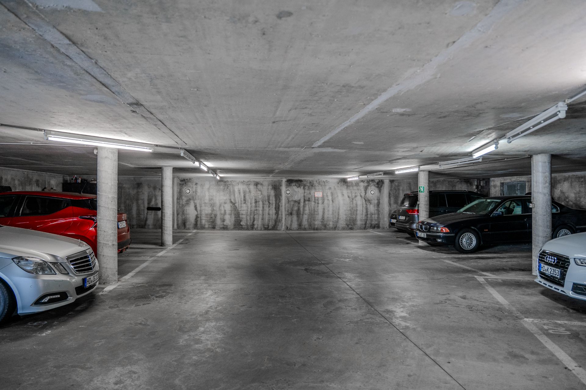 Tiefgaragenparkplatz mit mehreren geparkten Autos und Betonpfeilern.