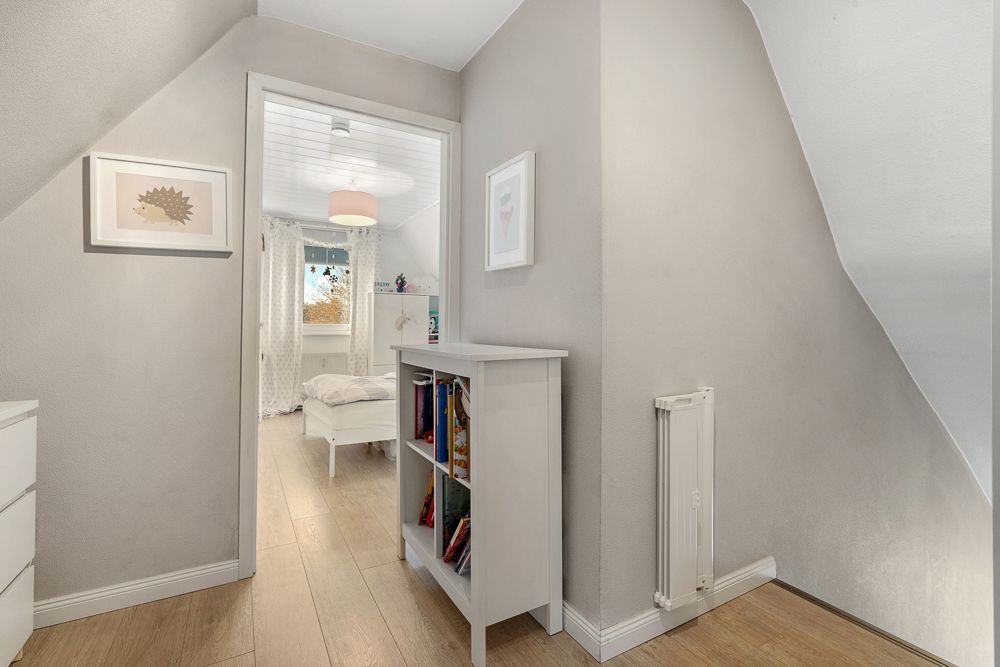 Heller Flur mit Regal und Blick in ein Kinderzimmer mit Bett und Fenster.