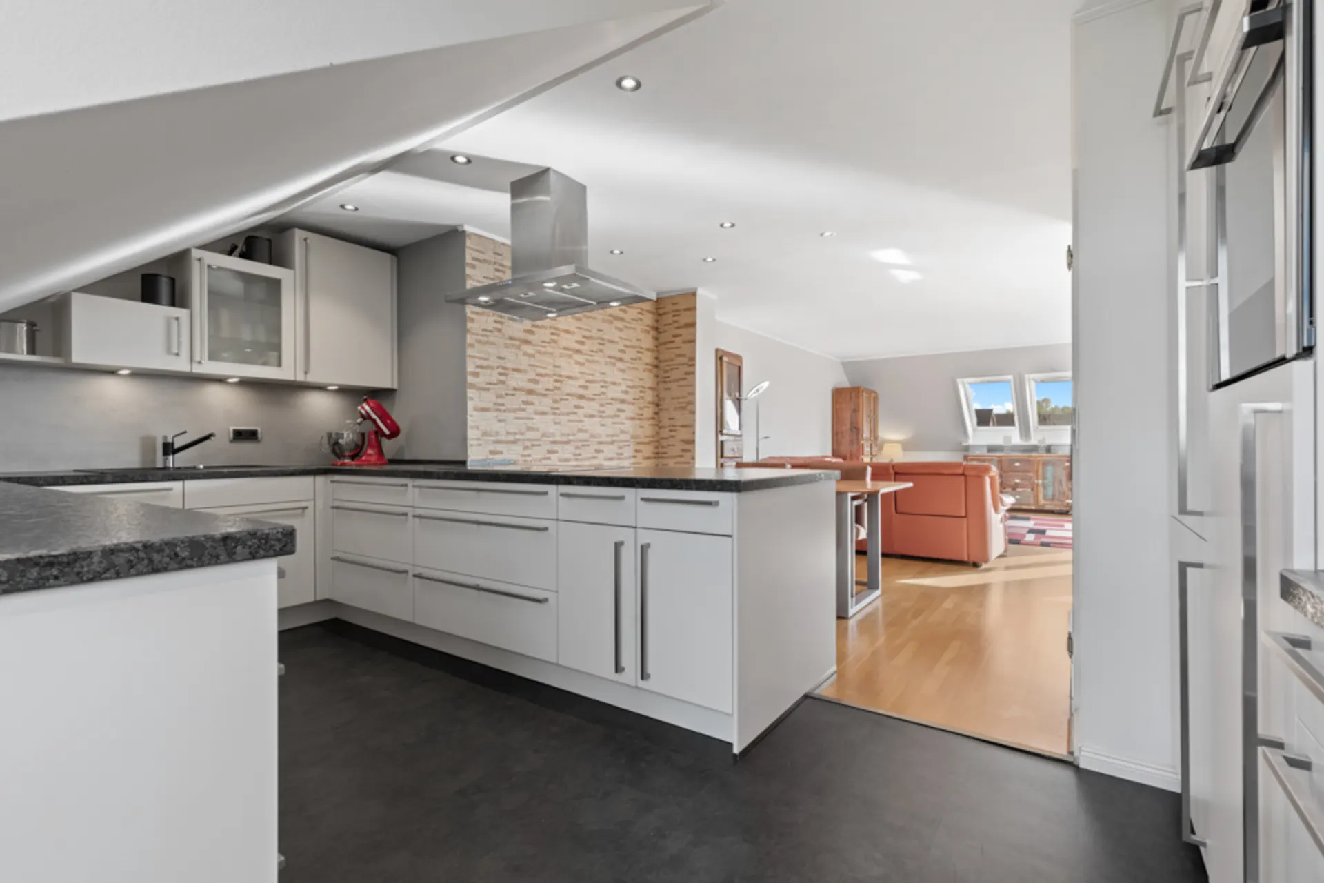 Moderne Einbauküche mit Kücheninsel, offenem Grundriss und Blick ins helle Wohnzimmer.