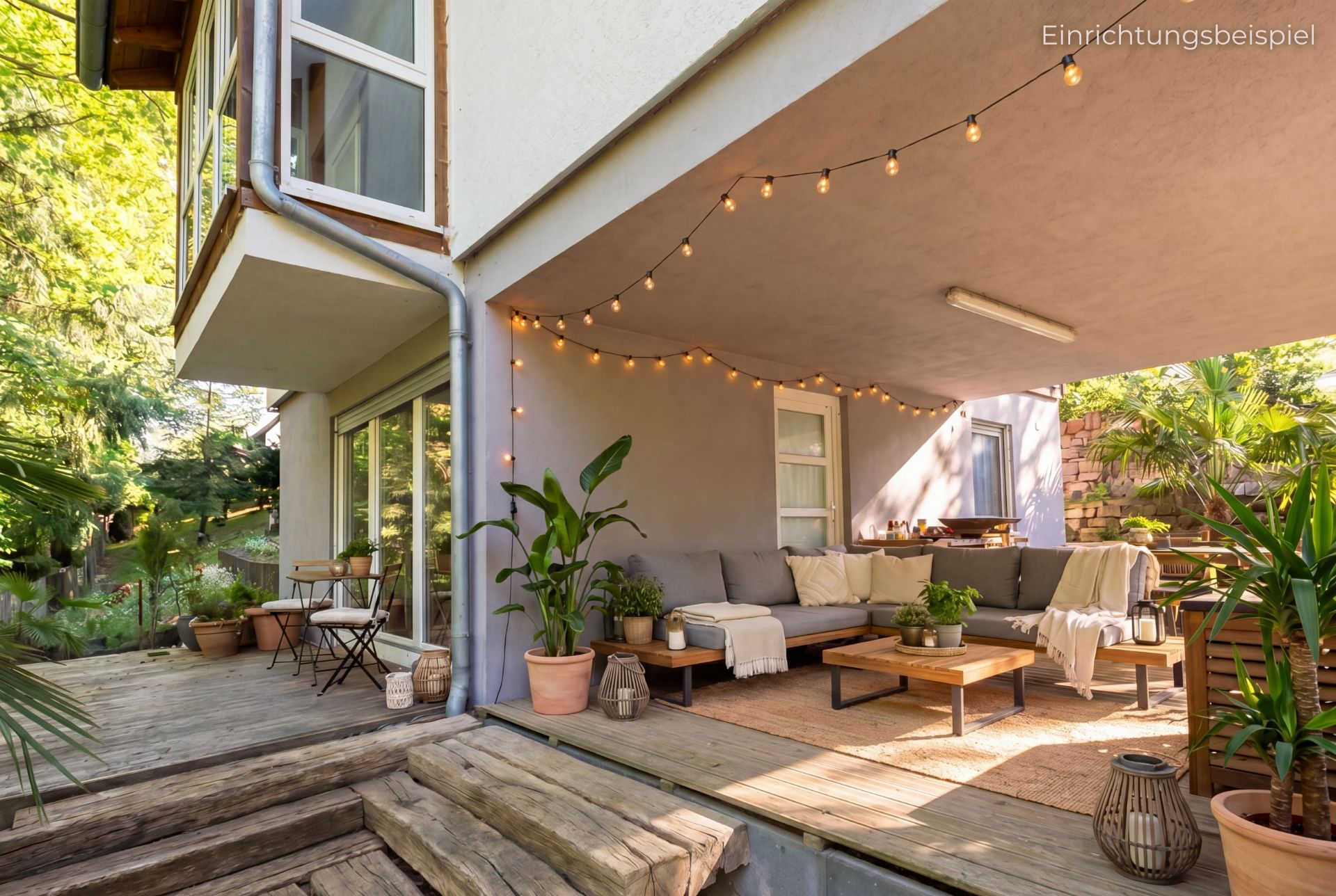 Überdachte Terrasse mit Lichterkette, Sitzgruppe, Pflanzen und Holzboden an einem Wohnhaus.
