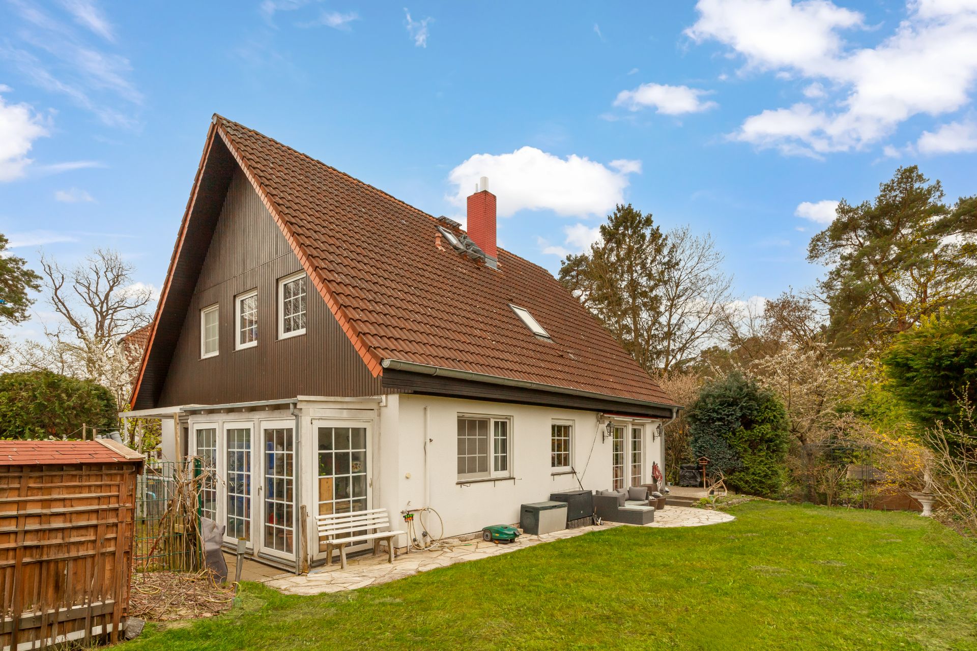 Einfamilienhaus mit rotem Satteldach, Wintergarten und Garten im Grünen.