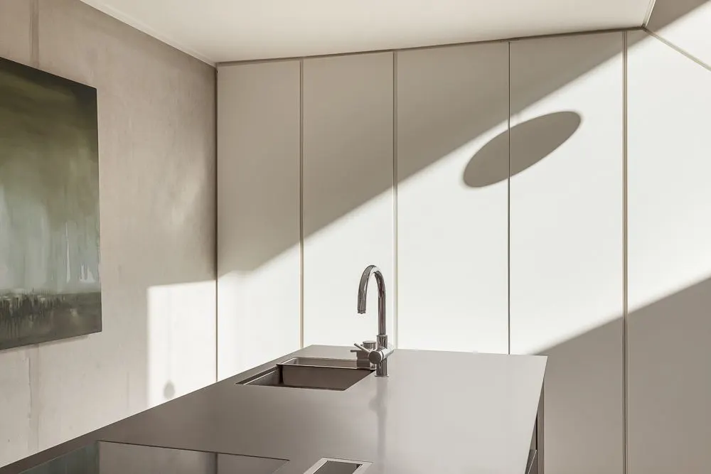 Moderne Küche mit glänzender Arbeitsplatte, Spüle, Wasserhahn und abstraktem Bild an der Wand.