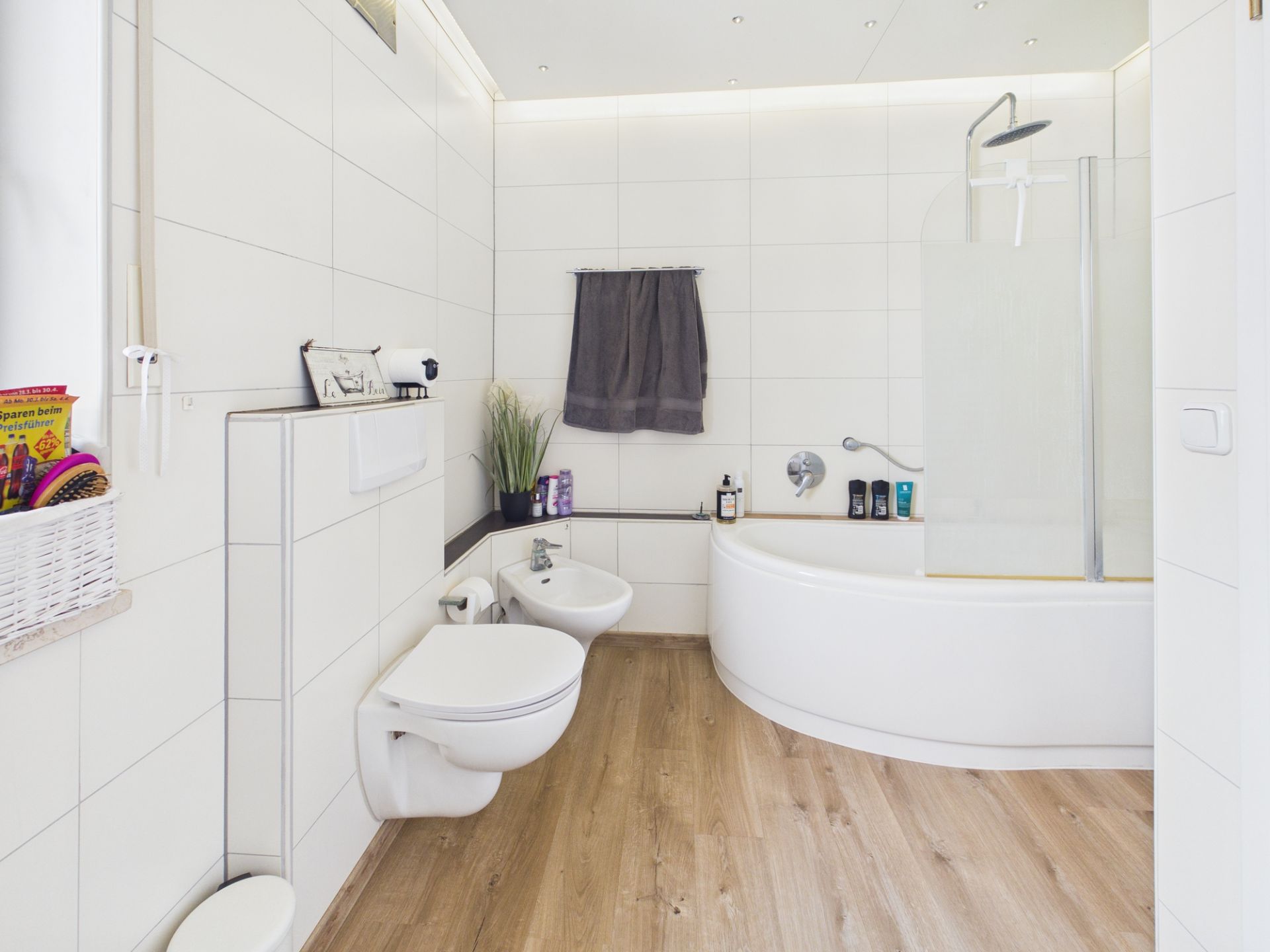 Modernes Badezimmer mit Badewanne, WC, Bidet und Holzfußboden.