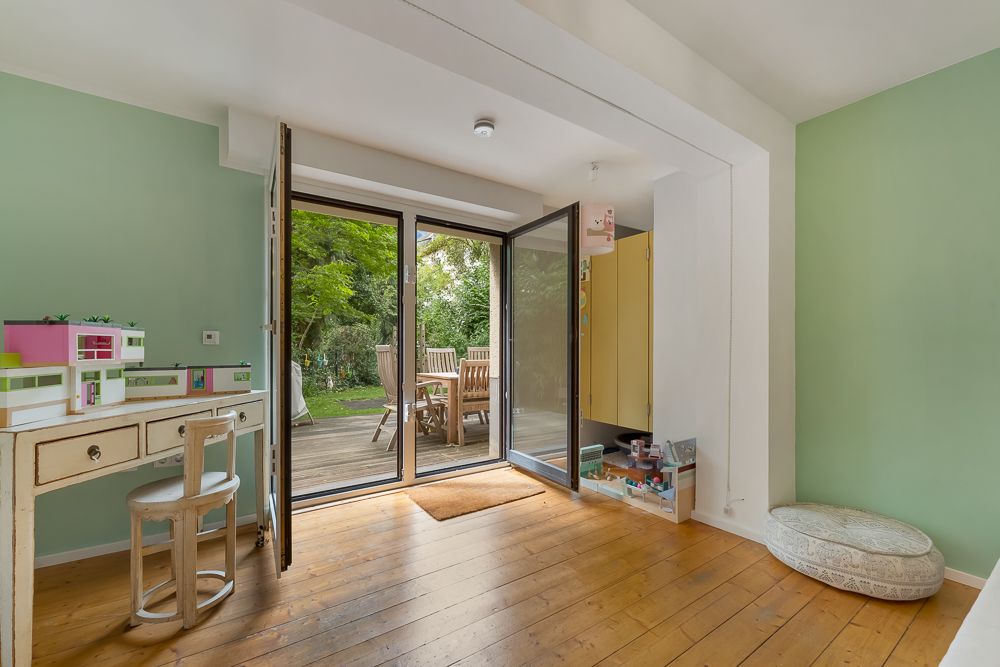 Helles Zimmer mit Schreibtisch, offenem Fenster zur Terrasse und Blick auf den Garten.