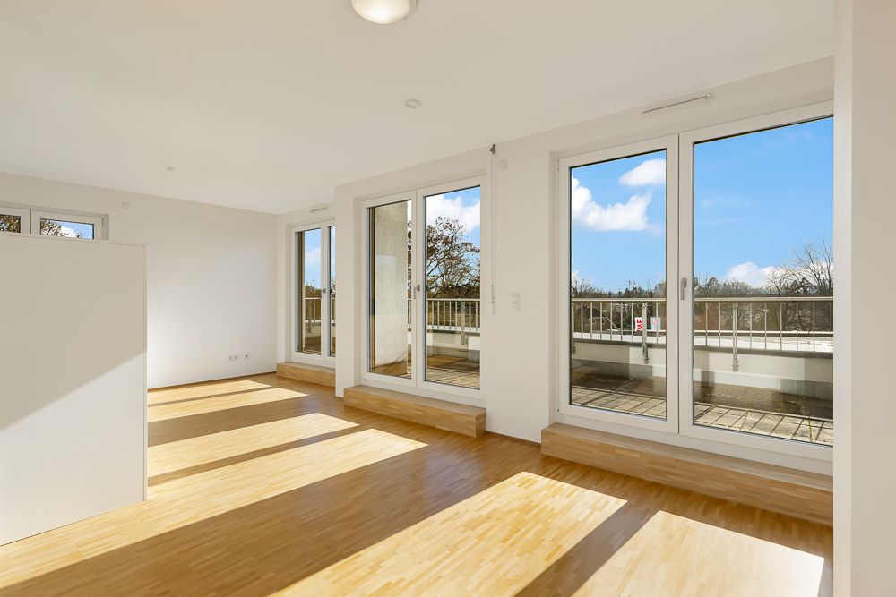 Helles Wohnzimmer mit Parkettboden und großen Fenstern zu einem Balkon.