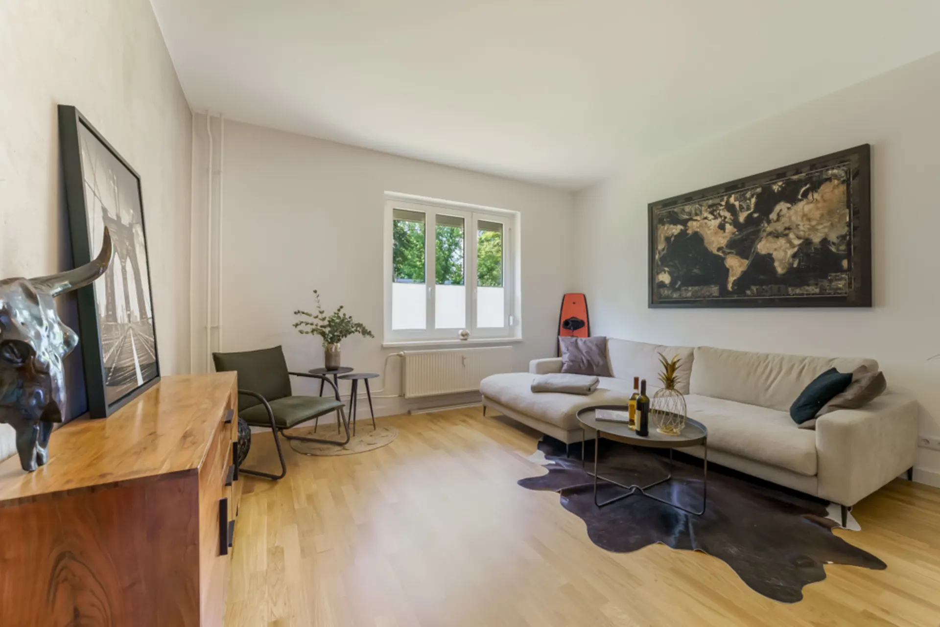 Modernes Wohnzimmer mit Ecksofa, Couchtisch, Sessel und großem Weltkartenbild an der Wand.