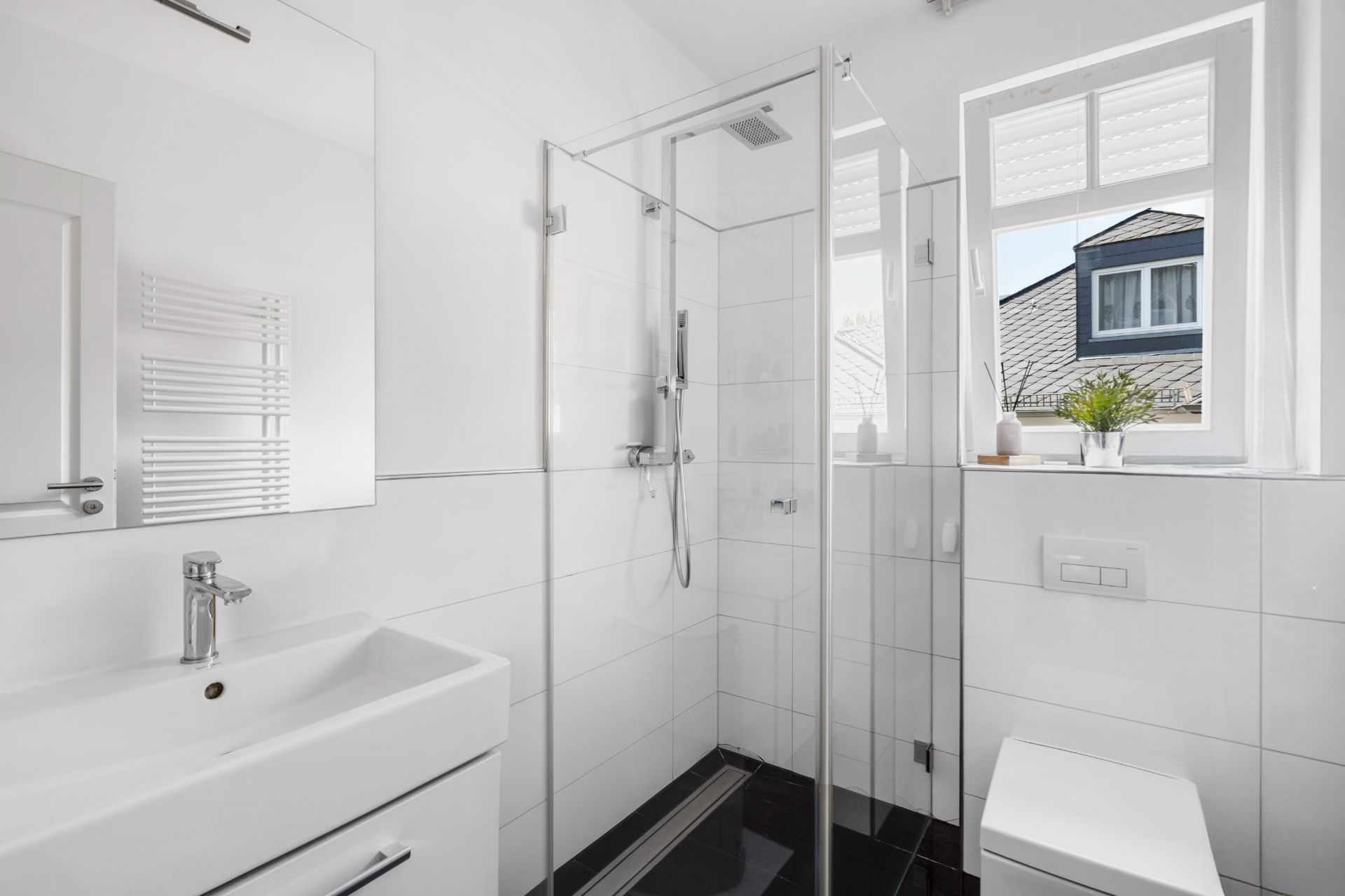 Modernes, helles Badezimmer mit Dusche, Waschbecken, Toilette und Fenster.