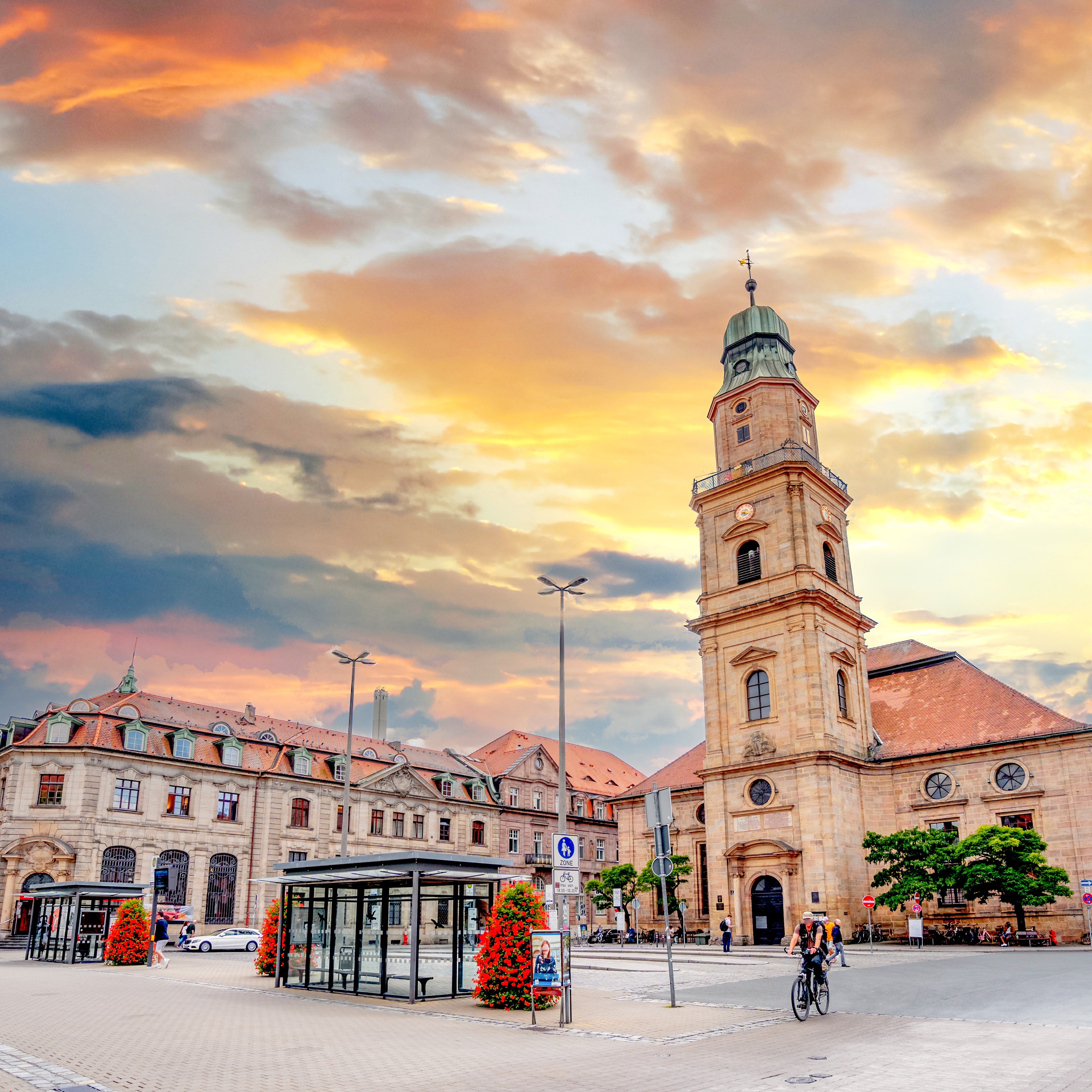 Historisches Gebäude mit Turm auf einem großen Platz bei Sonnenuntergang.