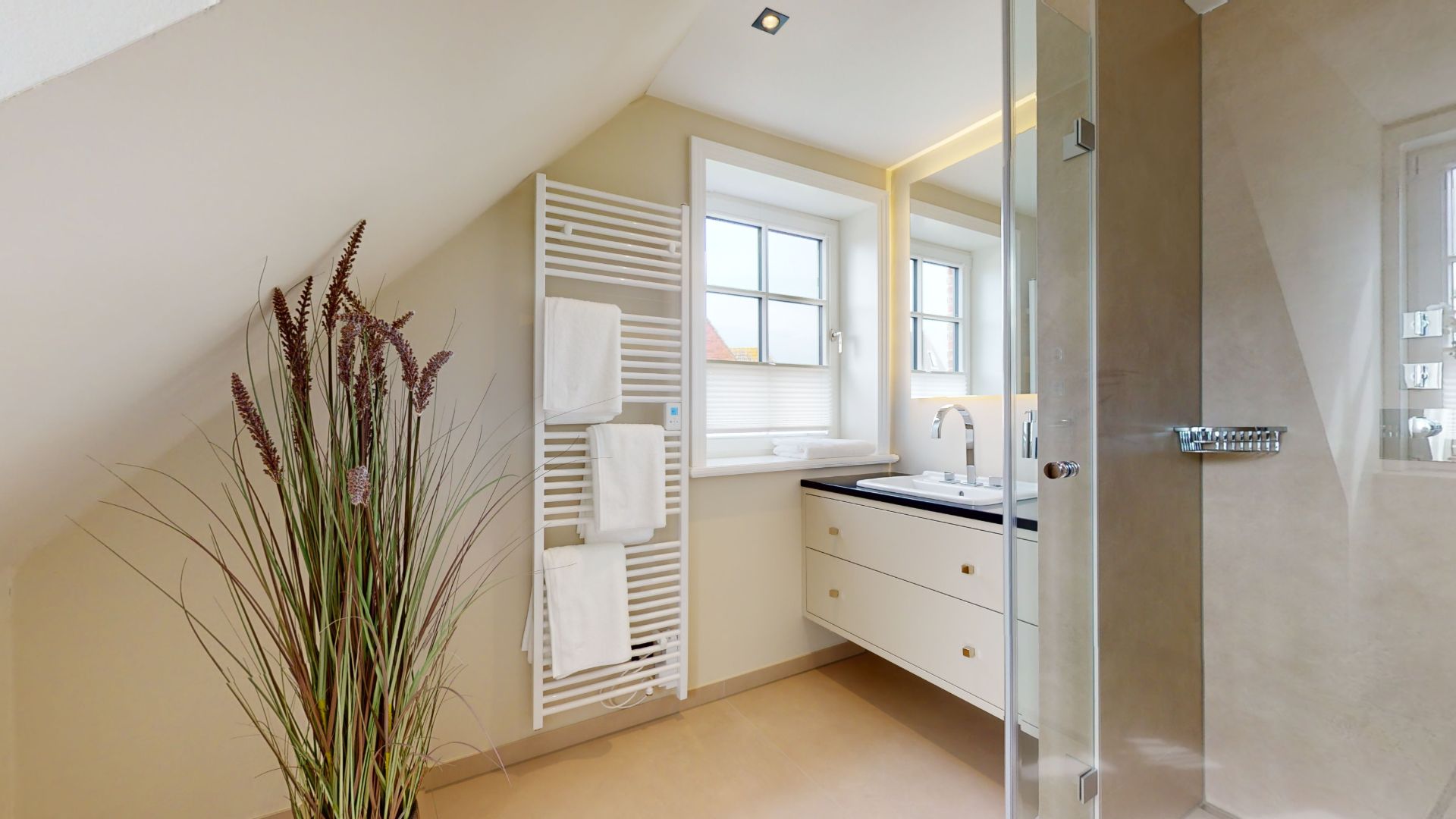 Modernes Badezimmer mit Dusche, Waschtisch, Handtuchheizkörper und Pflanze unter Dachschräge.