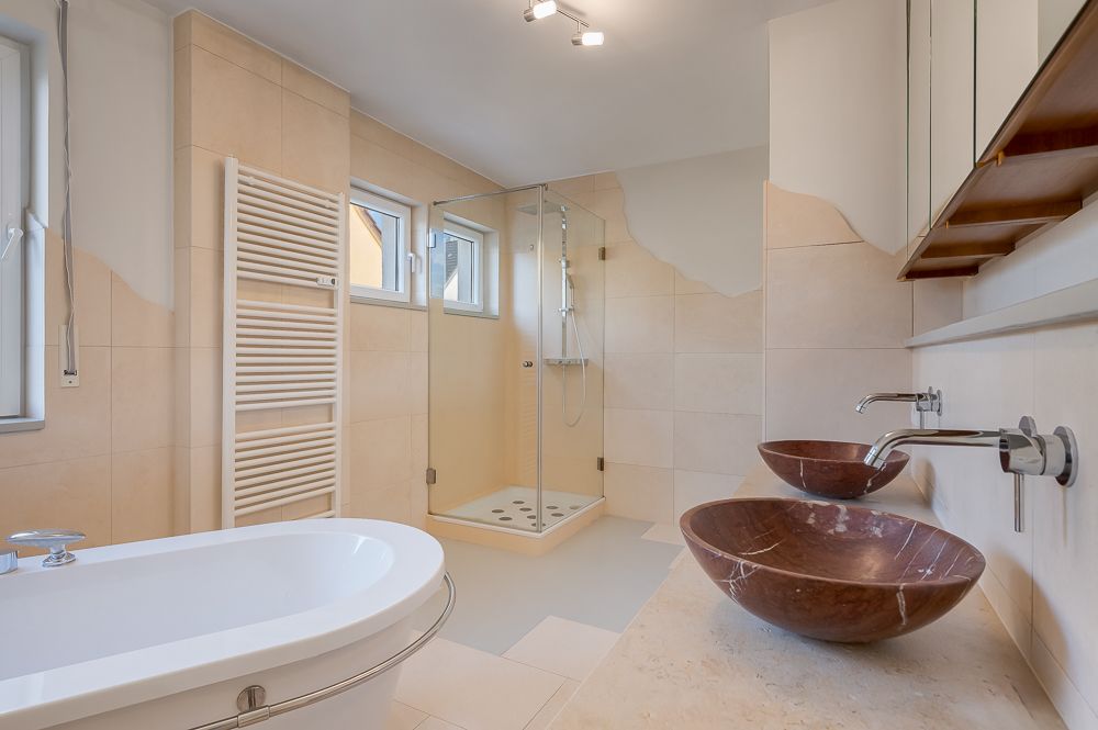 Modernes Badezimmer mit Badewanne, zwei Waschbecken und ebenerdiger Dusche.
