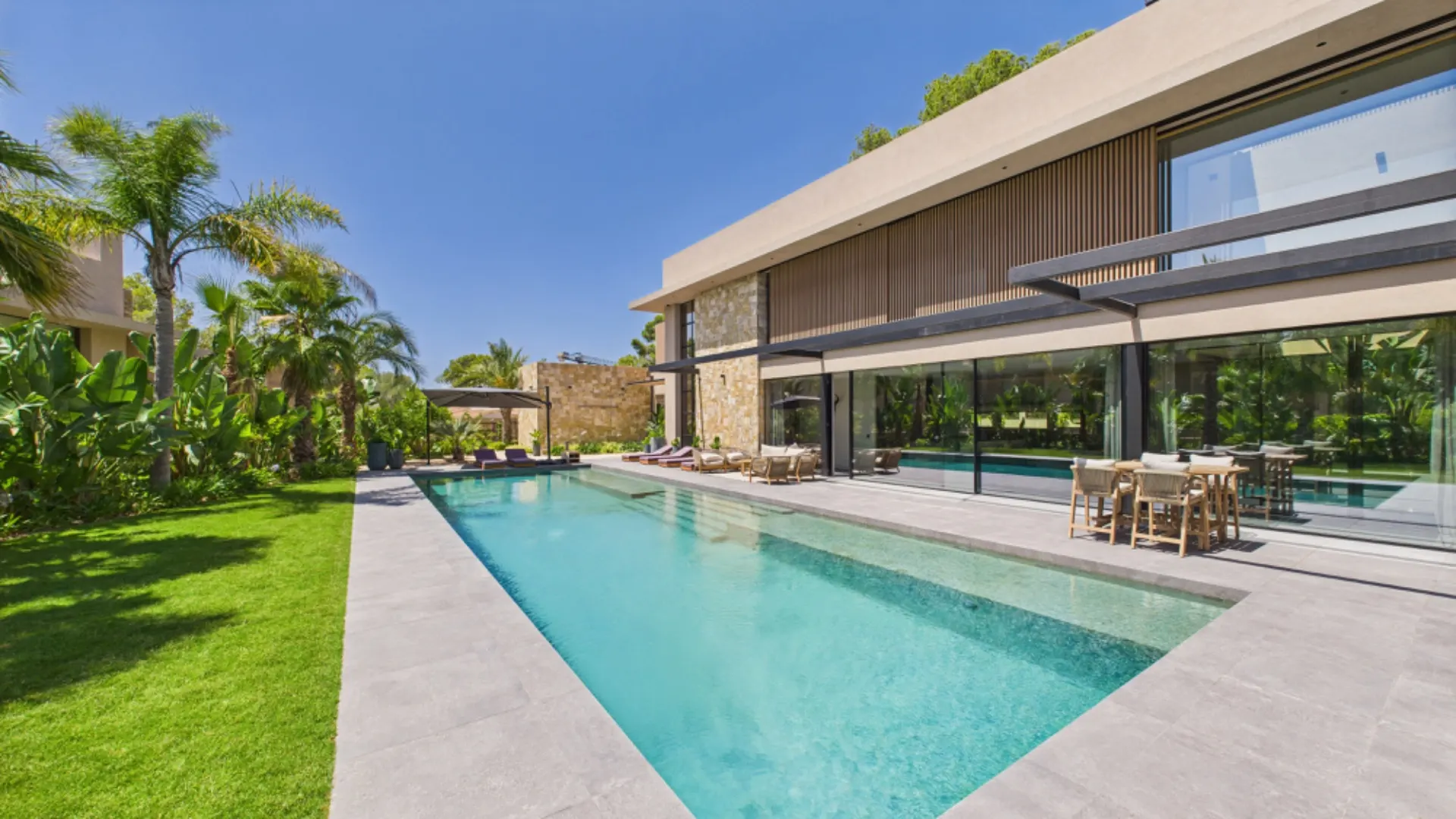 Moderner Garten mit langem Pool, Terrasse und Sitzbereich an einem Wohnhaus.