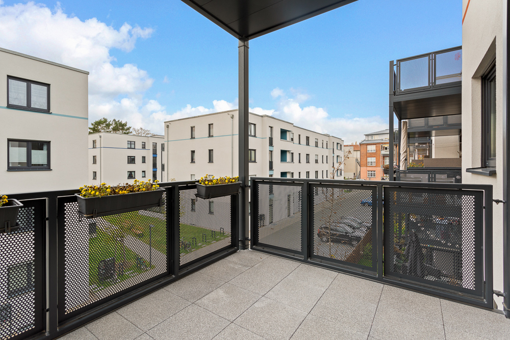 Balkon mit Metallgeländer und Blumenkästen, Blick auf moderne Wohngebäude.