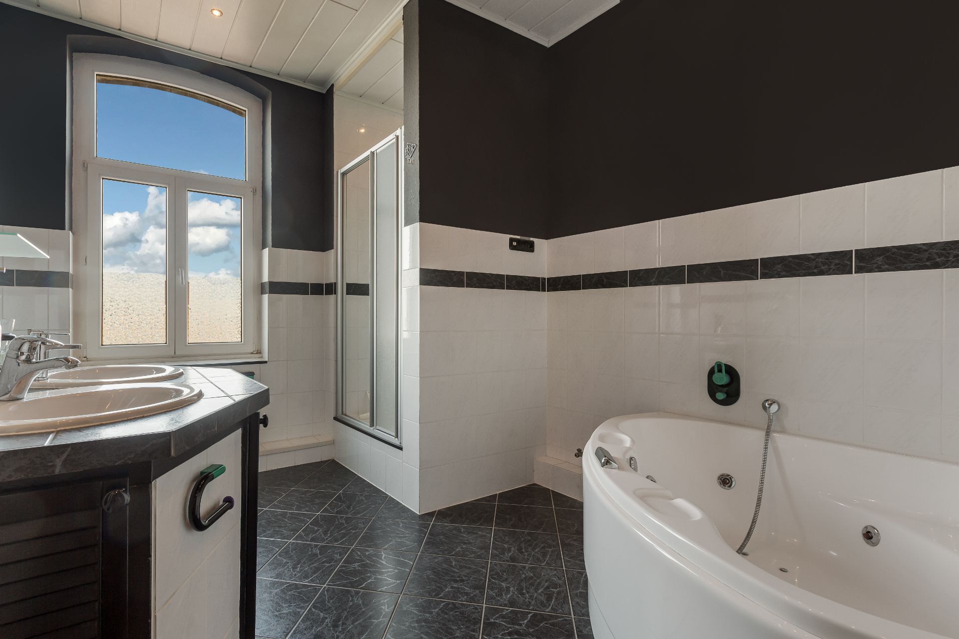 Modernes Badezimmer mit Eckbadewanne, Dusche, Doppelwaschbecken und großem Fenster.
