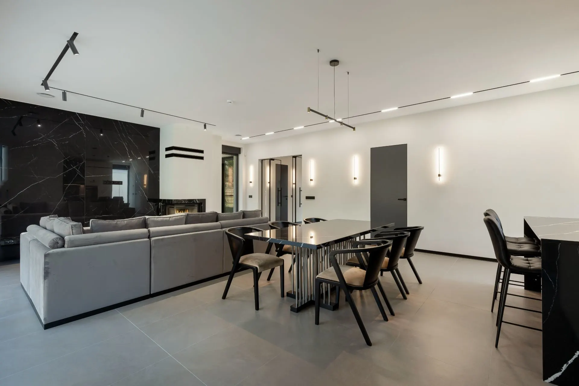 Modernes Wohnzimmer mit grauem Sofa, Esstisch mit Stühlen und offener Küche.