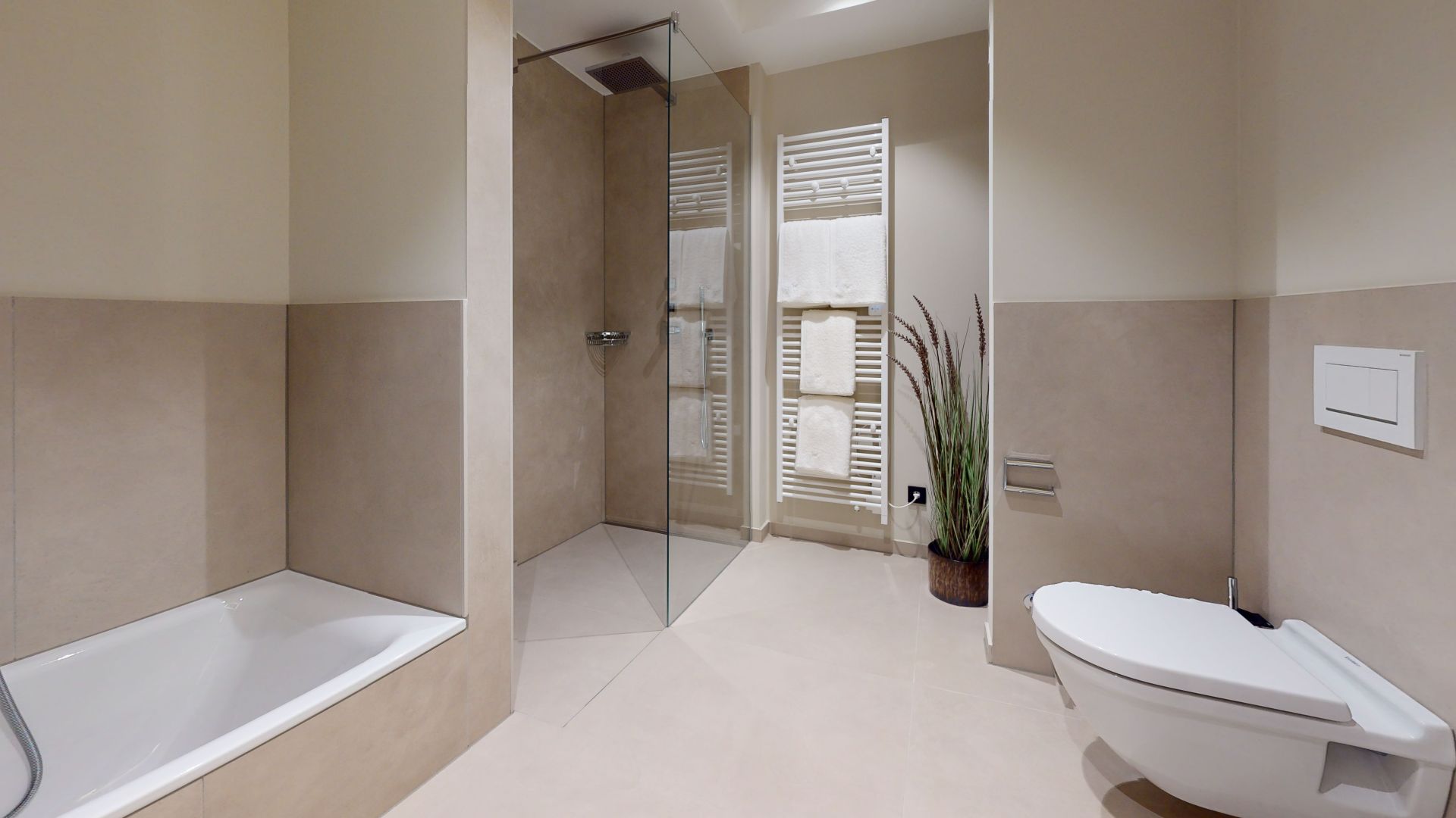 Modernes Badezimmer mit Badewanne, Dusche, WC, Handtuchheizkörper und Pflanze.