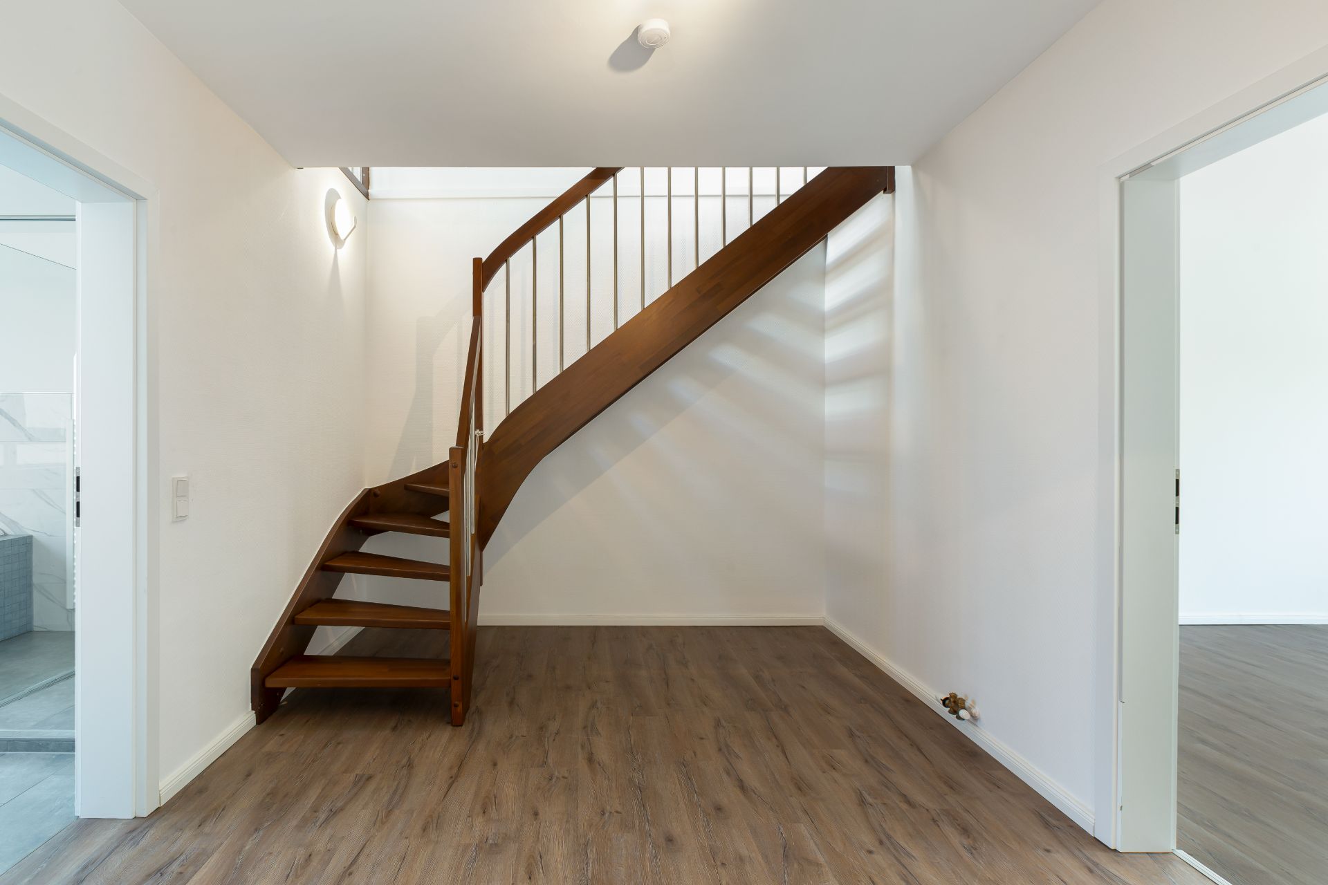 Holztreppe in einem hellen Raum mit Laminatboden und weißen Wänden.