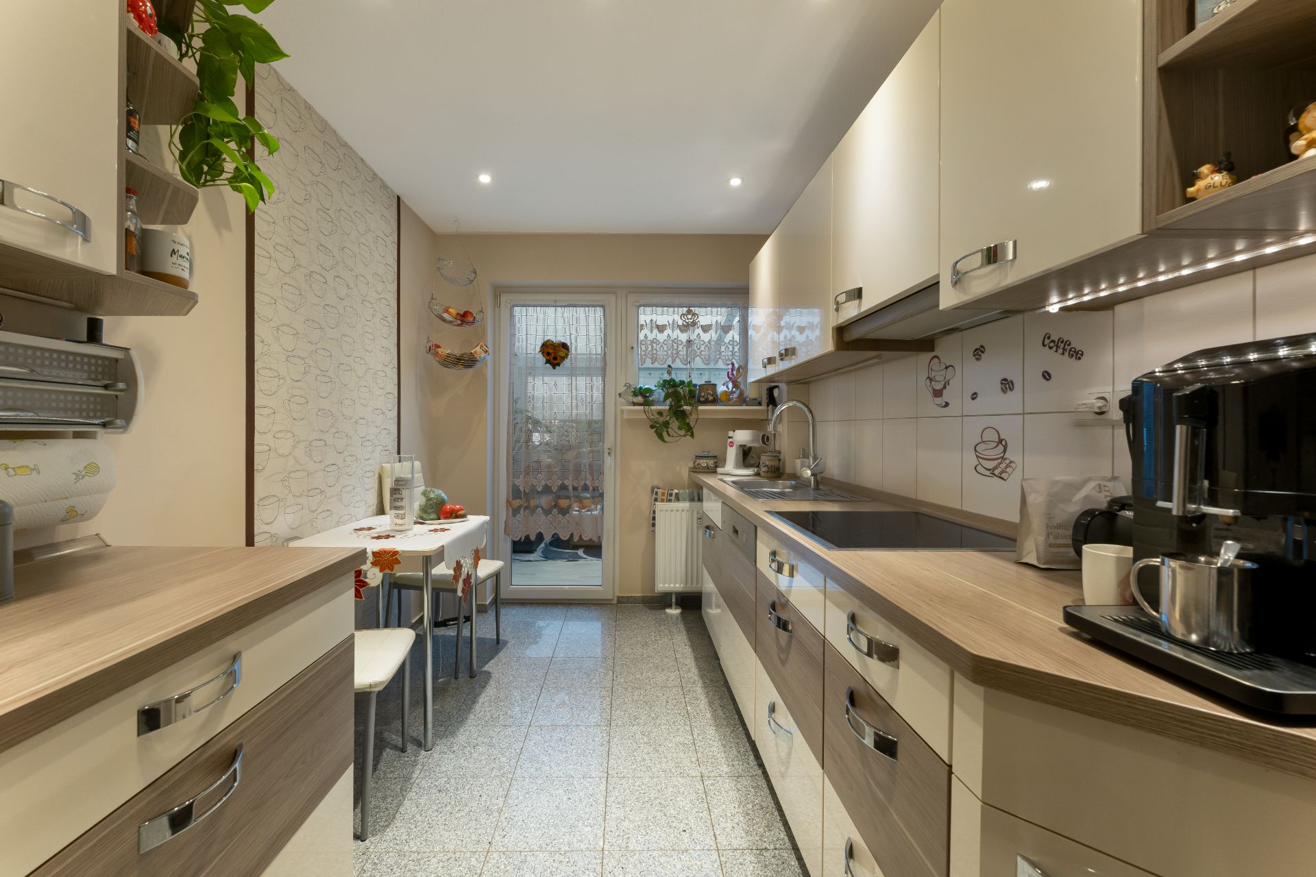 Moderne Küche mit langen Arbeitsplatten, kleinem Esstisch und Fenster zum Garten.