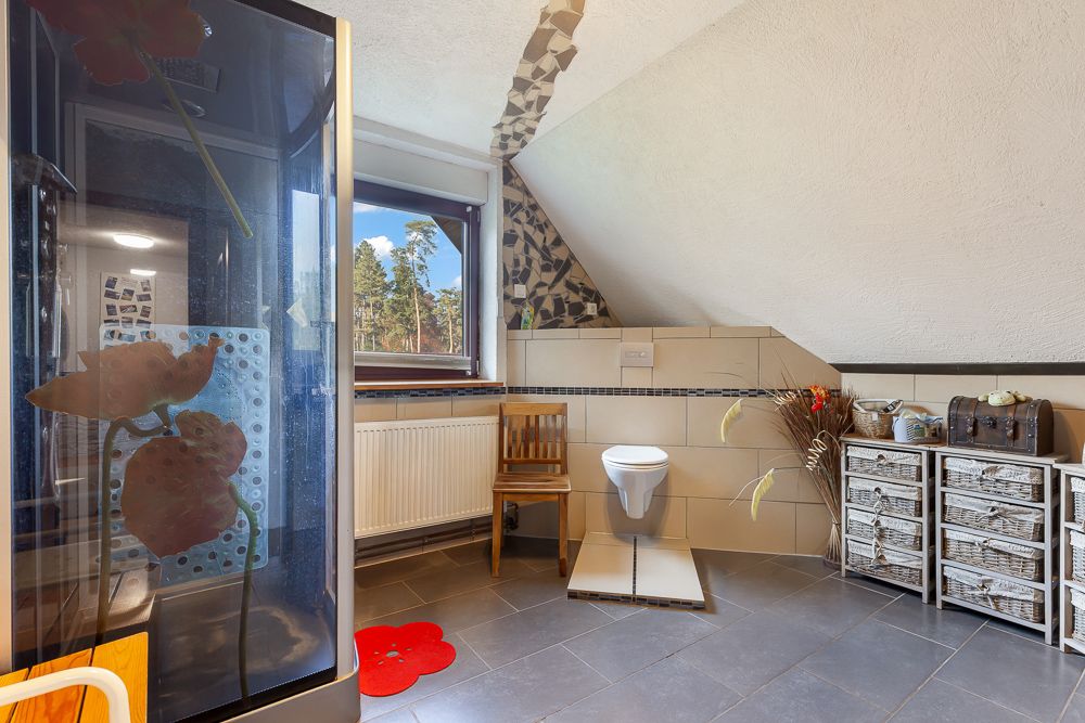 Modernes Badezimmer mit Dusche, Wandtoilette, Fenster und geflochtenen Schubladen.