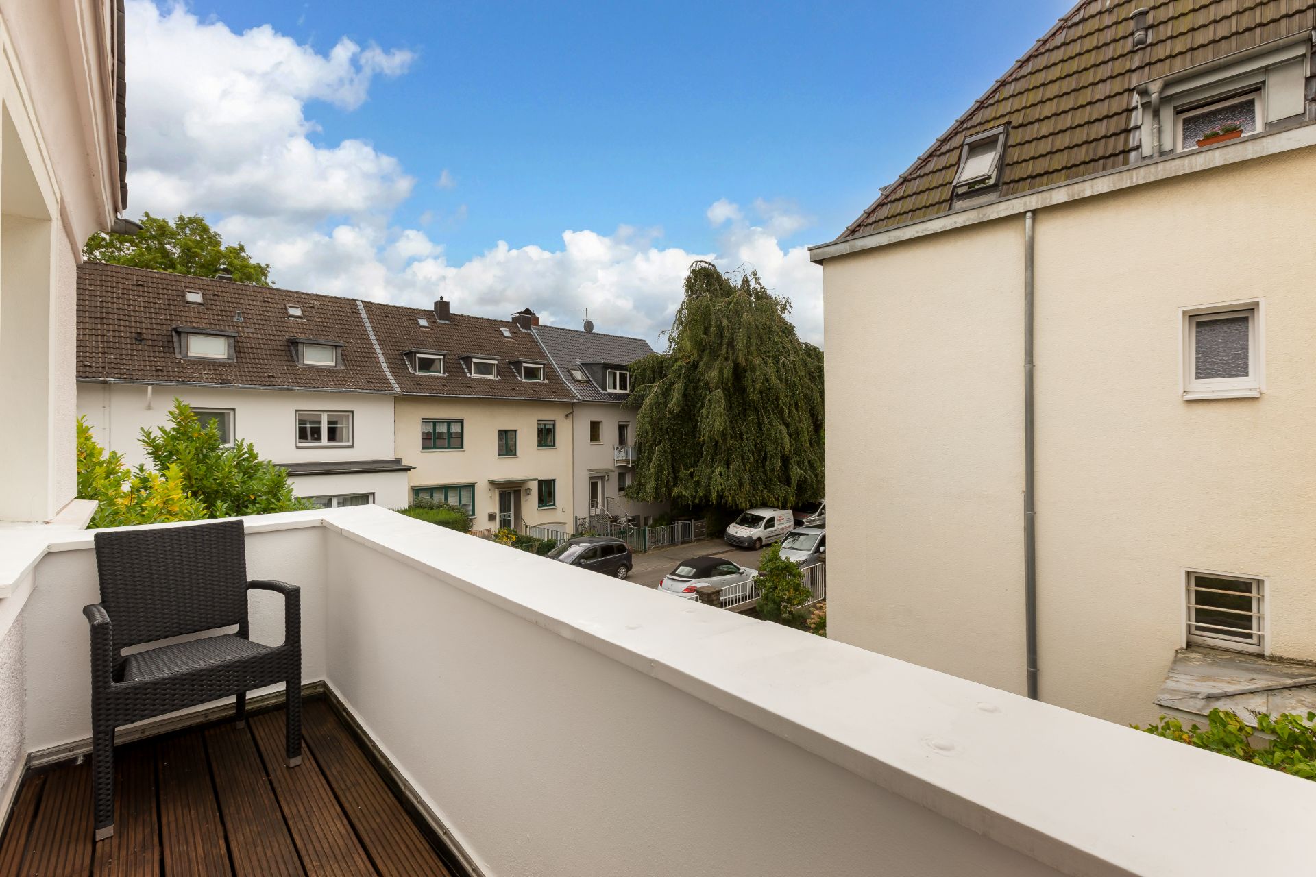 Balkon mit Stuhl und Blick auf Wohnhäuser und eine ruhige Straße.