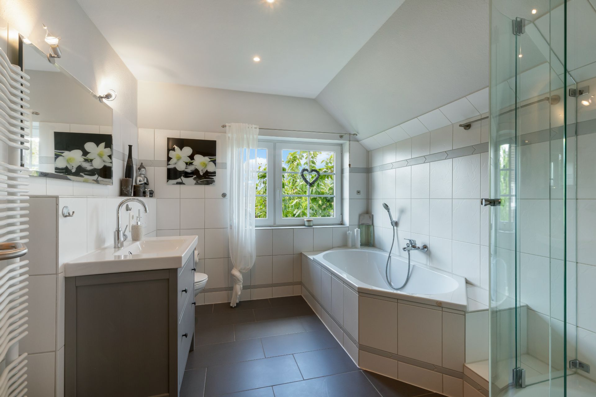 Modernes Badezimmer mit Eckbadewanne, Dusche, Fenster und großem Spiegel.