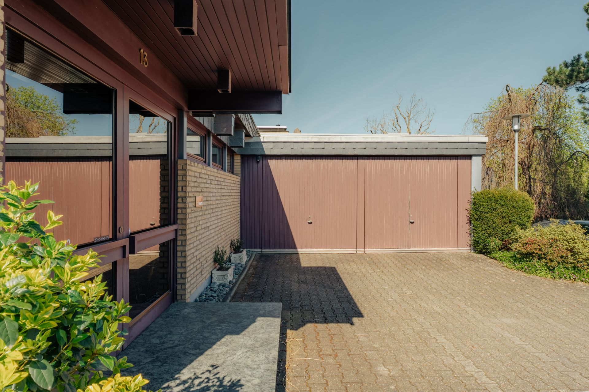 Vorhof eines Wohnhauses mit gepflasterter Einfahrt und großer Garage.