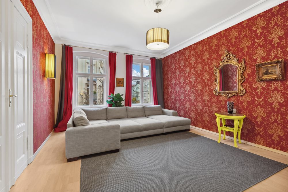 Wohnzimmer mit roter Tapete, grauem Sofa, gelbem Tisch und großem Fenster.