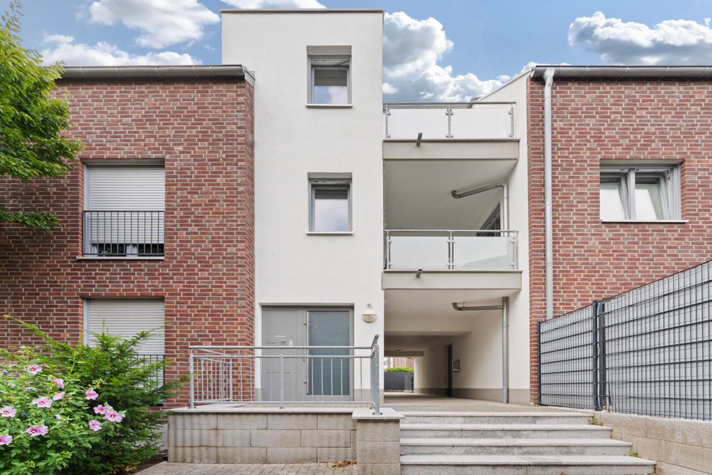 Eingangsbereich eines modernen Wohnhauses mit Backsteinfassade und Treppe.