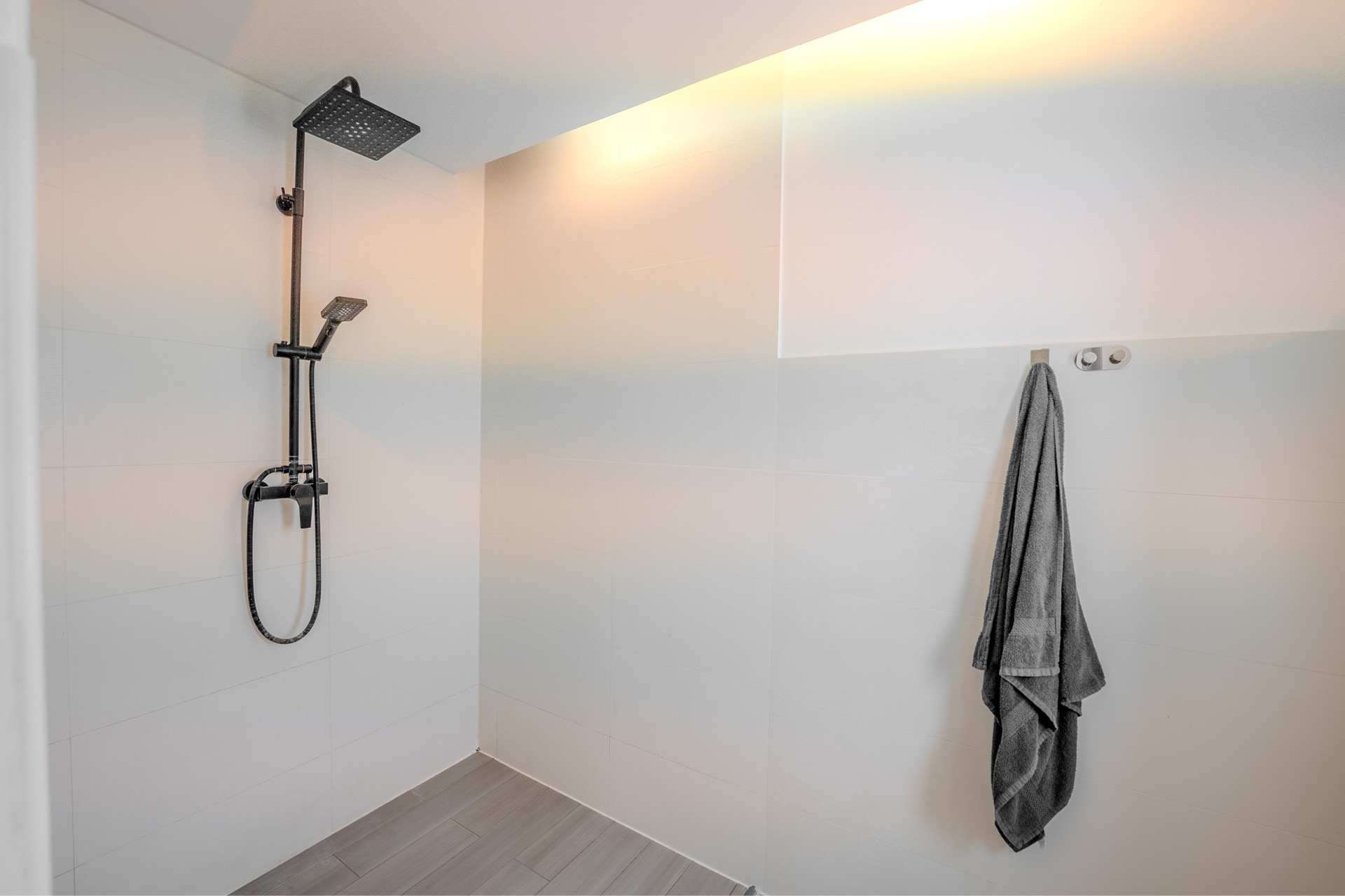 Moderne, offene Dusche mit Handtuch an einem Haken an der Wand.